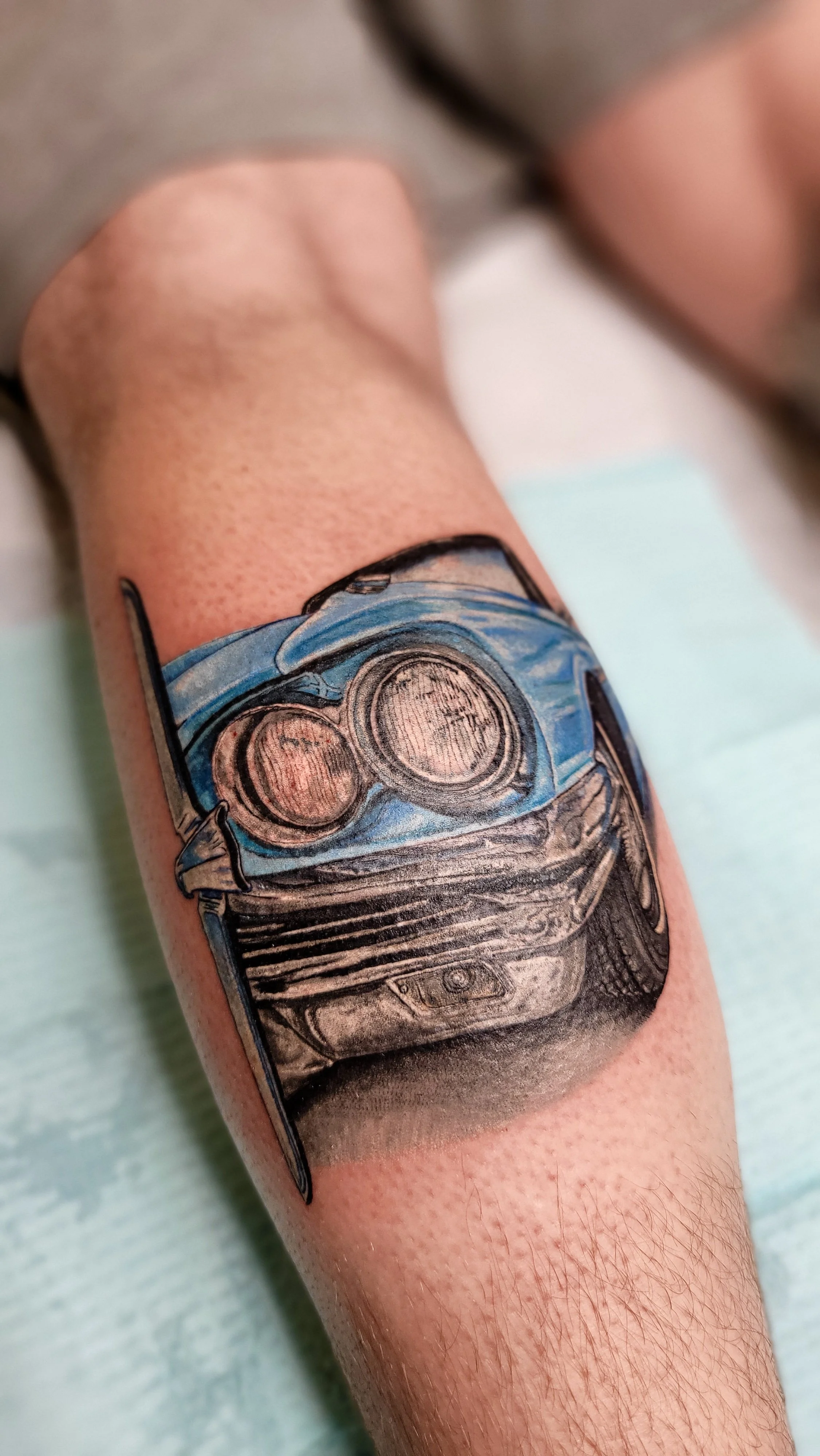 Tattoo of a car's front view with headlights on the person's arm.