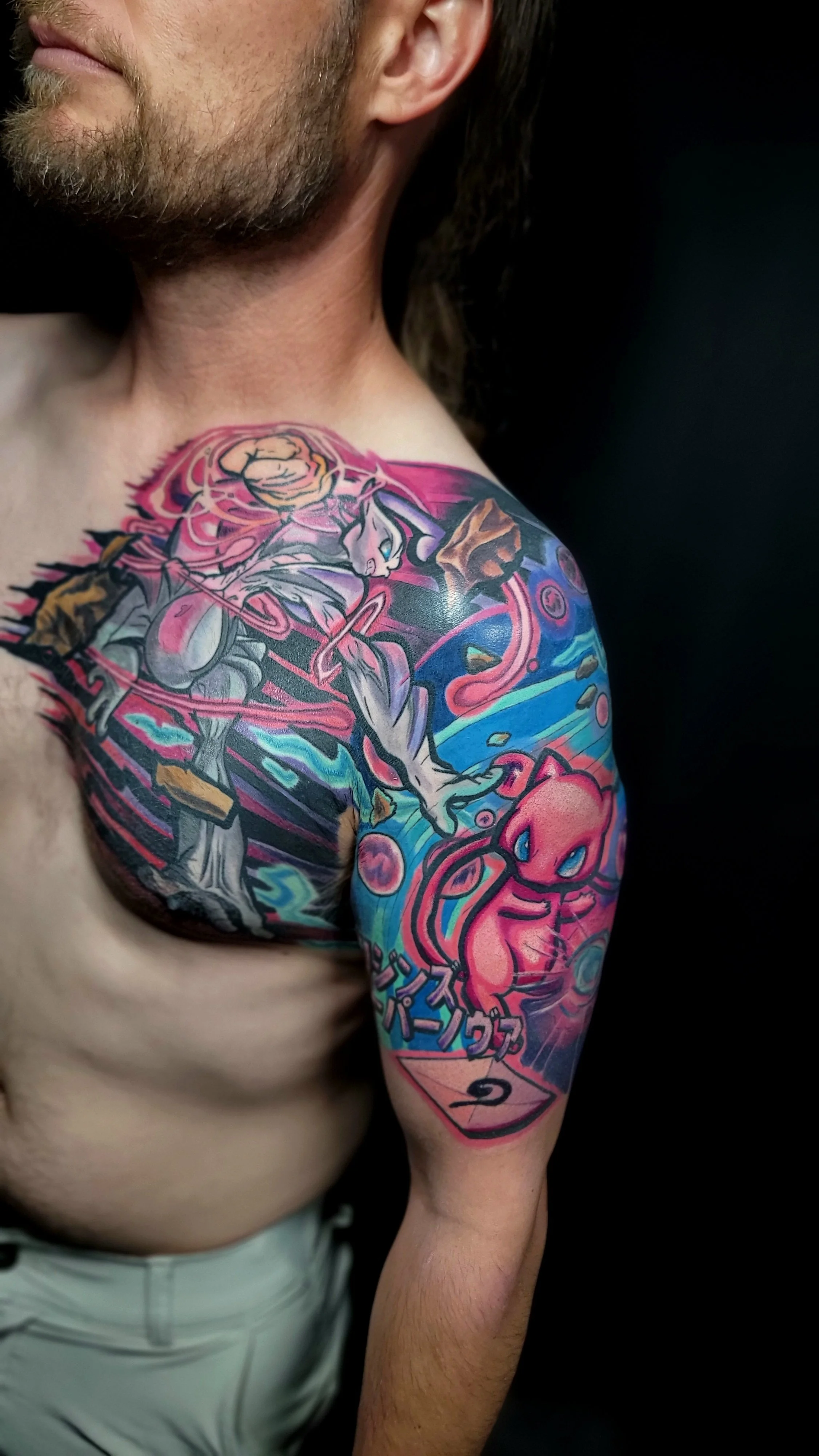 Colorful tattoo sleeve on the shoulder and upper arm featuring Pokémon characters, including Mewtwo and Charmander.