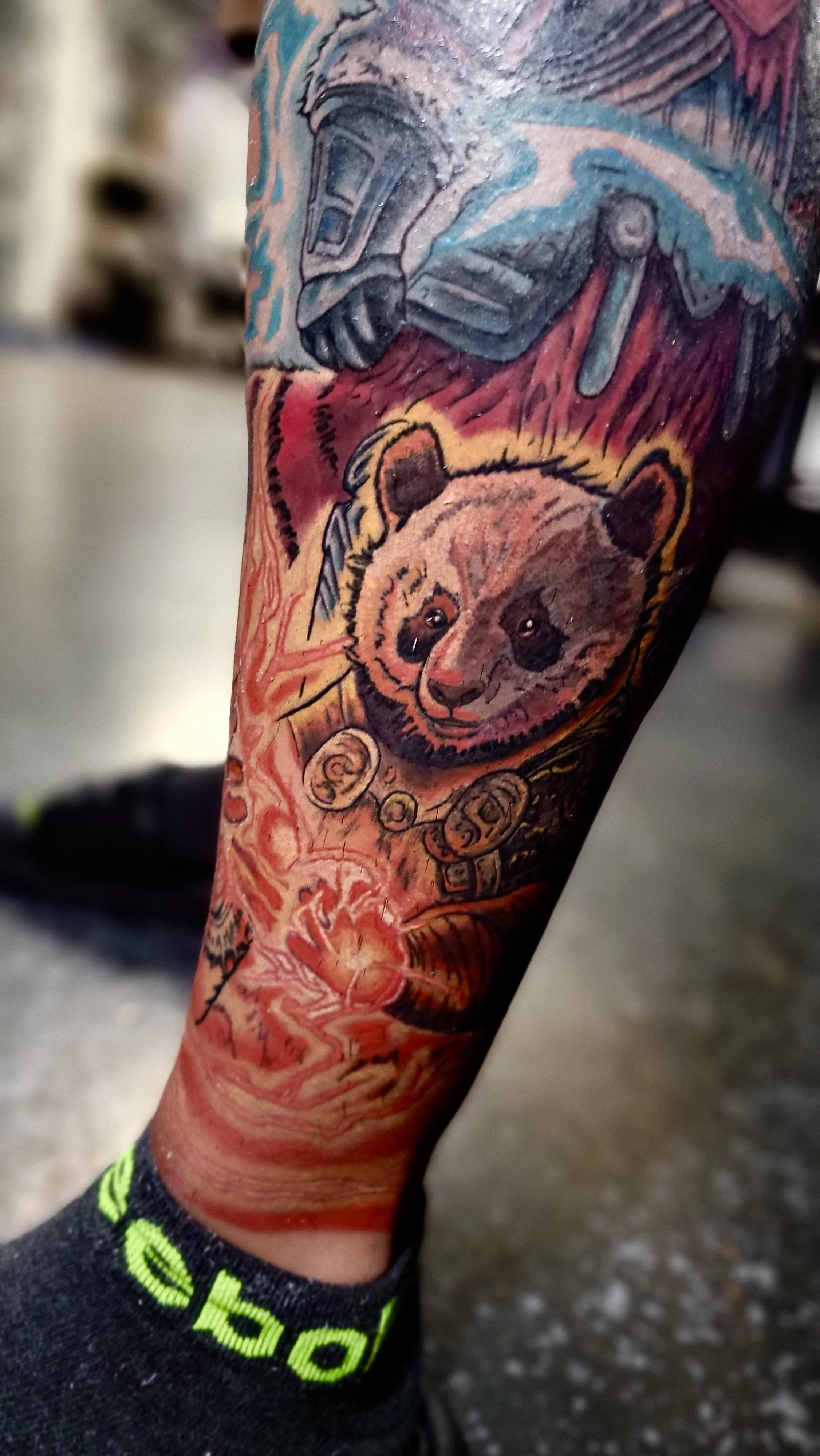 Colorful tattoo of a bear wearing a necklace on a person's arm.