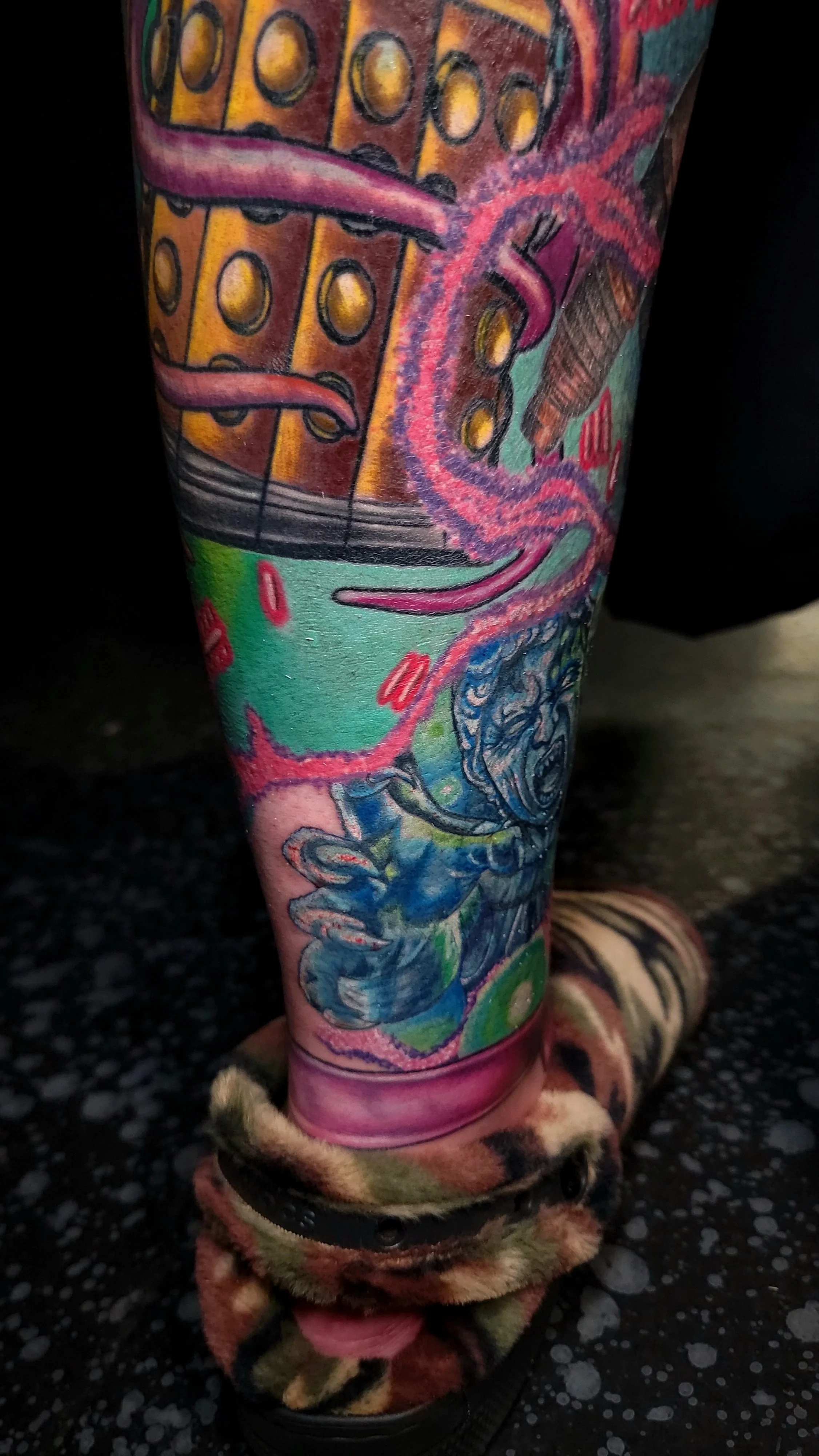 Colorful tattoo sleeve featuring a guitar, pink octopus tentacle, and various ocean-themed elements on a person's leg.