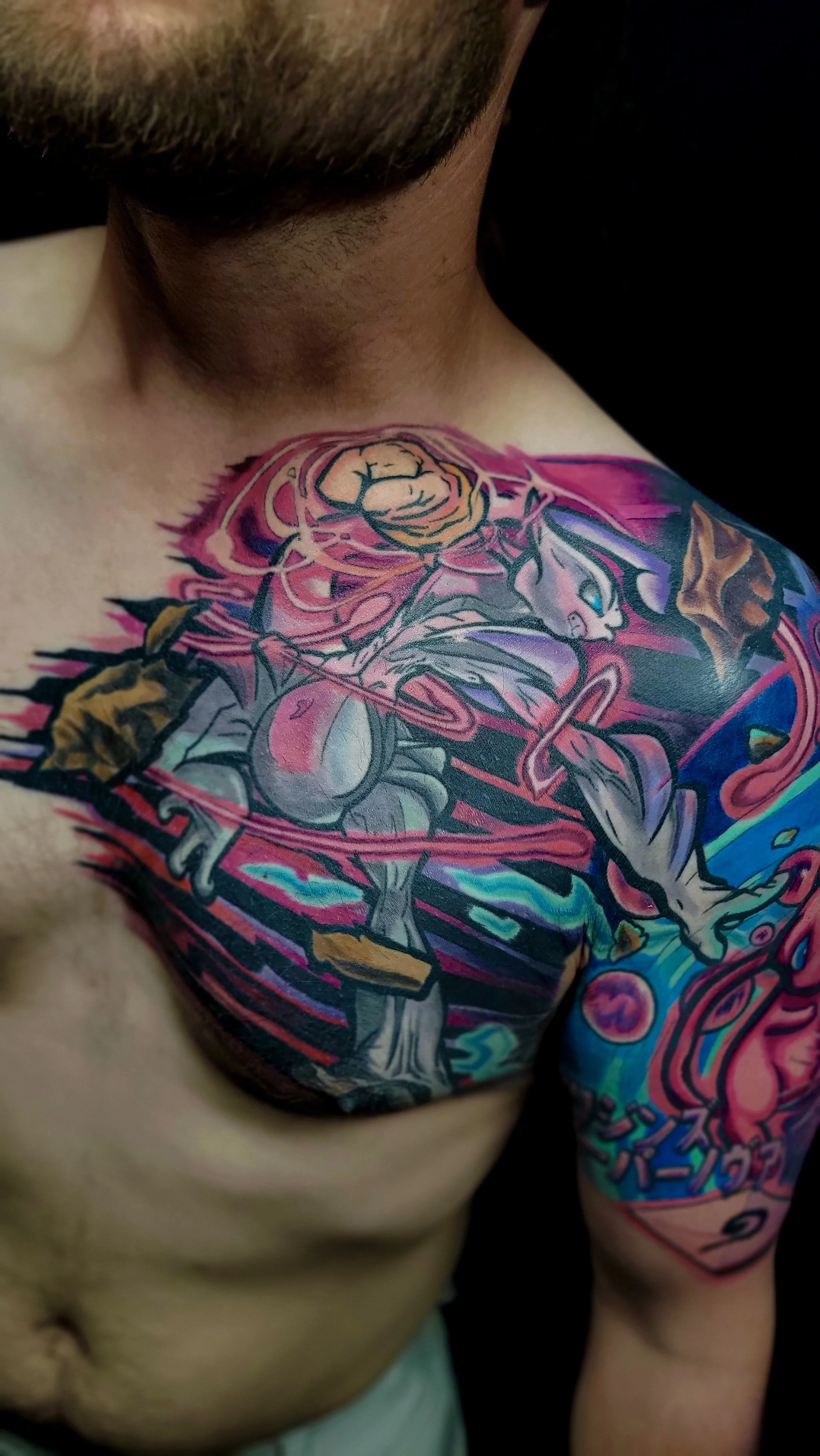 Close-up of a person's shoulder and chest displaying a colorful tattoo featuring a stylized cartoon character with a large head and exaggerated facial features, surrounded by swirling designs and vibrant colors.