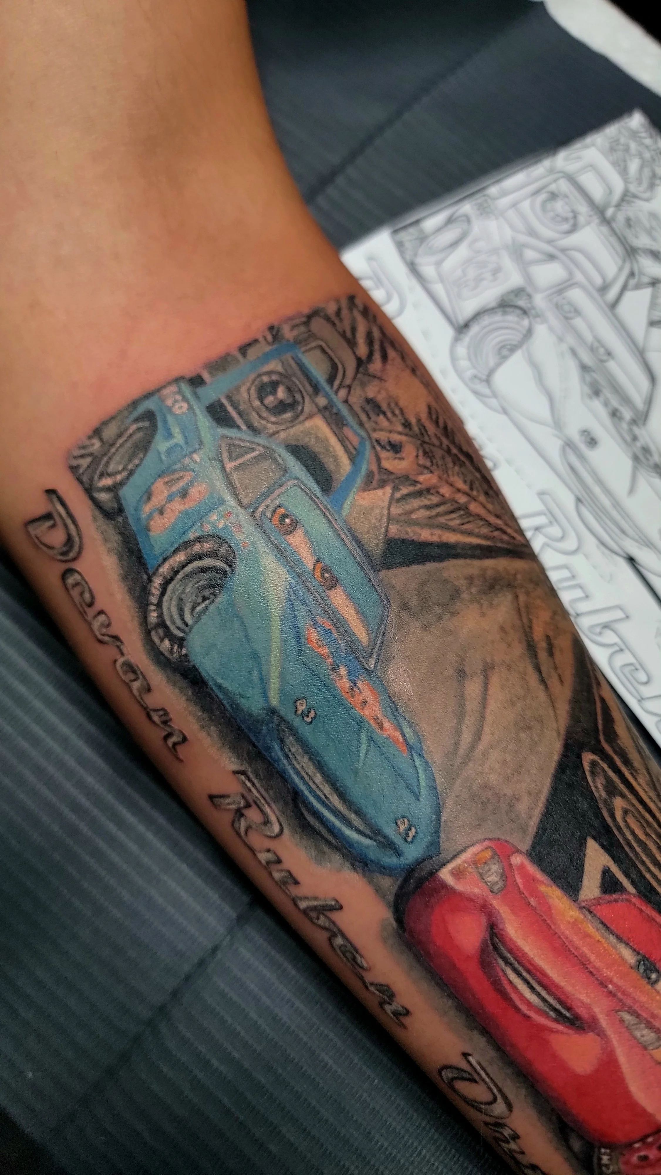 Colorful tattoo of a police car on a person's arm, with a drawing of a car and text surrounding it.
