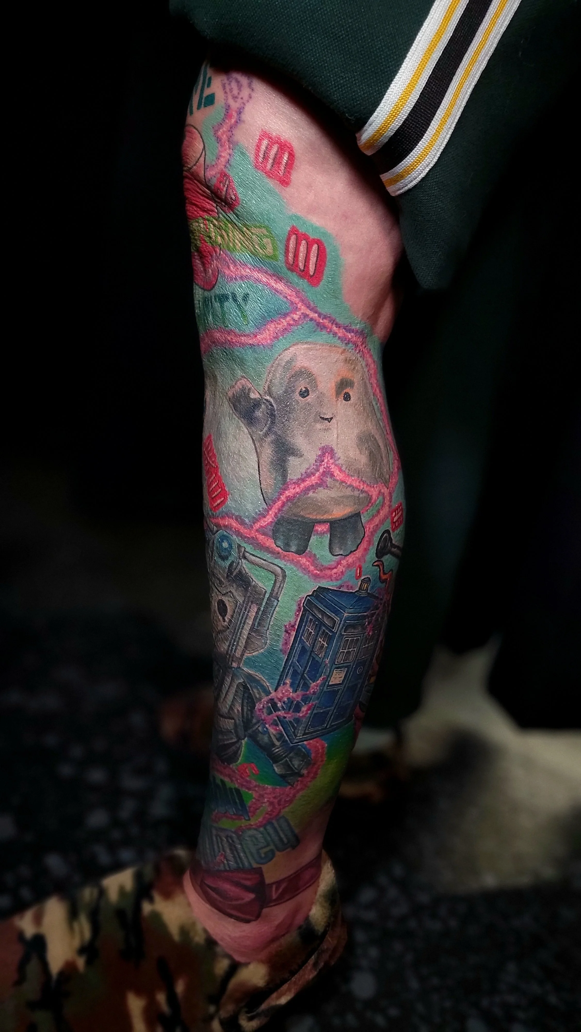 A tattoo of the TARDIS from Doctor Who, a Dalek, and a cartoon model of a sloth with donuts on its head, along with various scene elements from the show.