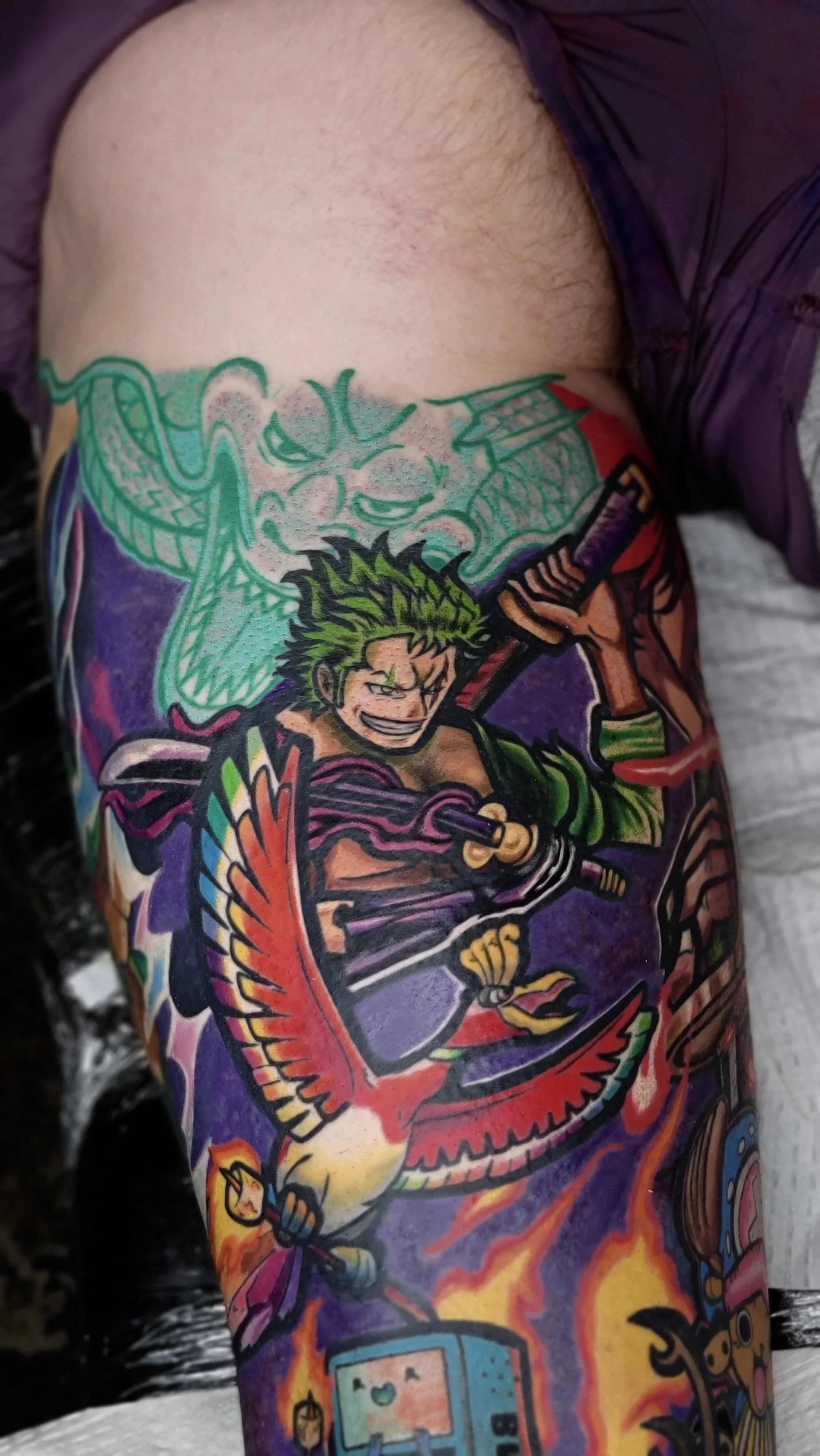 Colorful tattoo featuring a fierce warrior character wielding a sword and surrounded by flames.