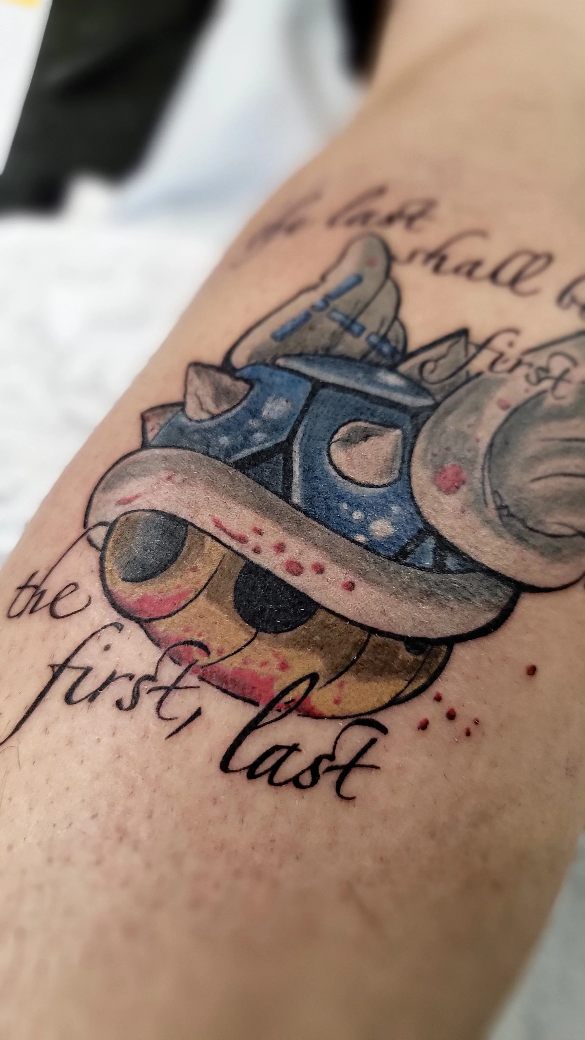 A tattoo on a person's arm featuring a colorful vintage car, with text that reads 'the first last' and cursive writing above and below the car.