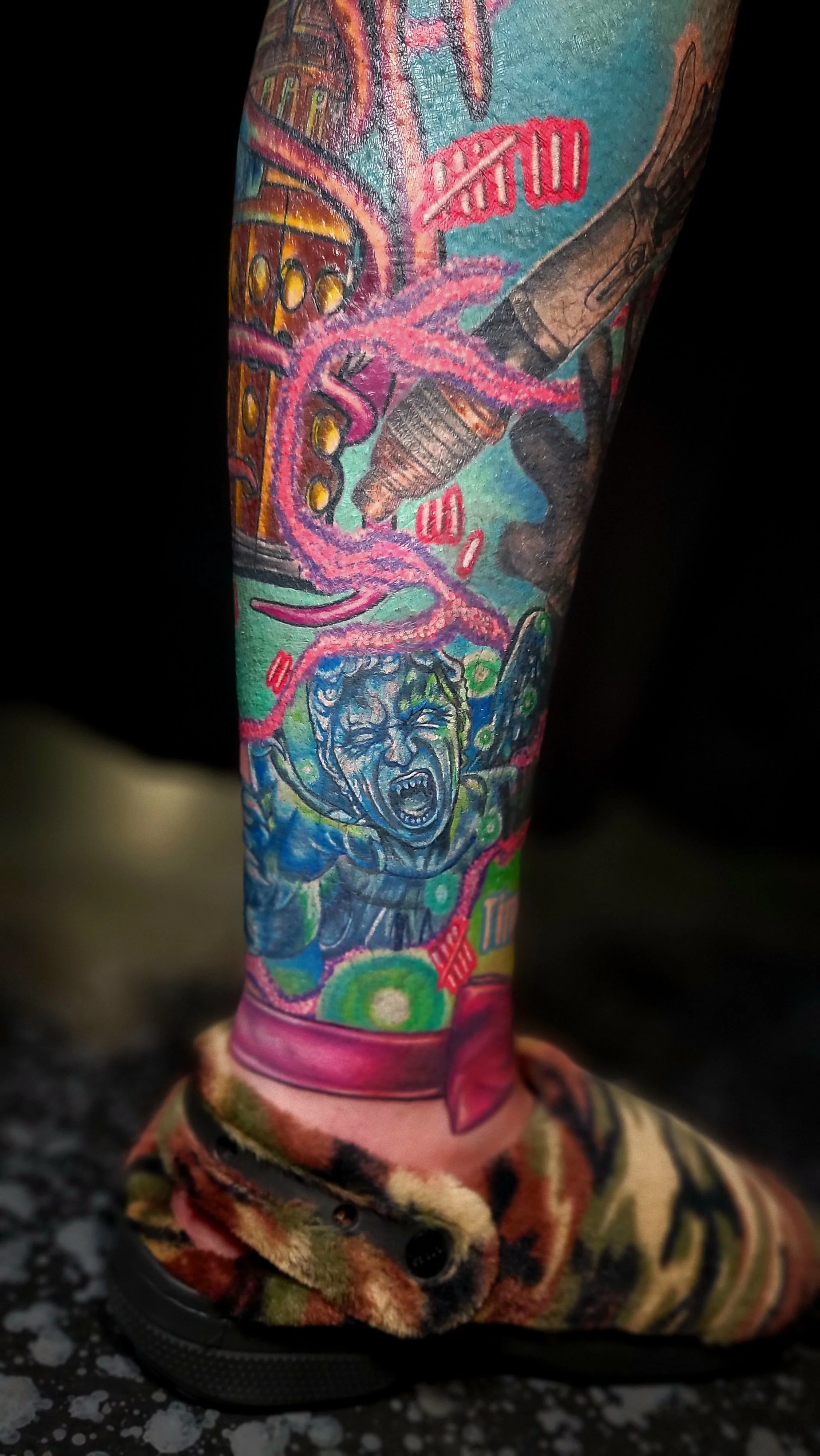 Colorful tattoo sleeve featuring a screaming woman, vibrant swirling patterns, a cassette tape, and various abstract designs, all on a person's lower leg and foot.