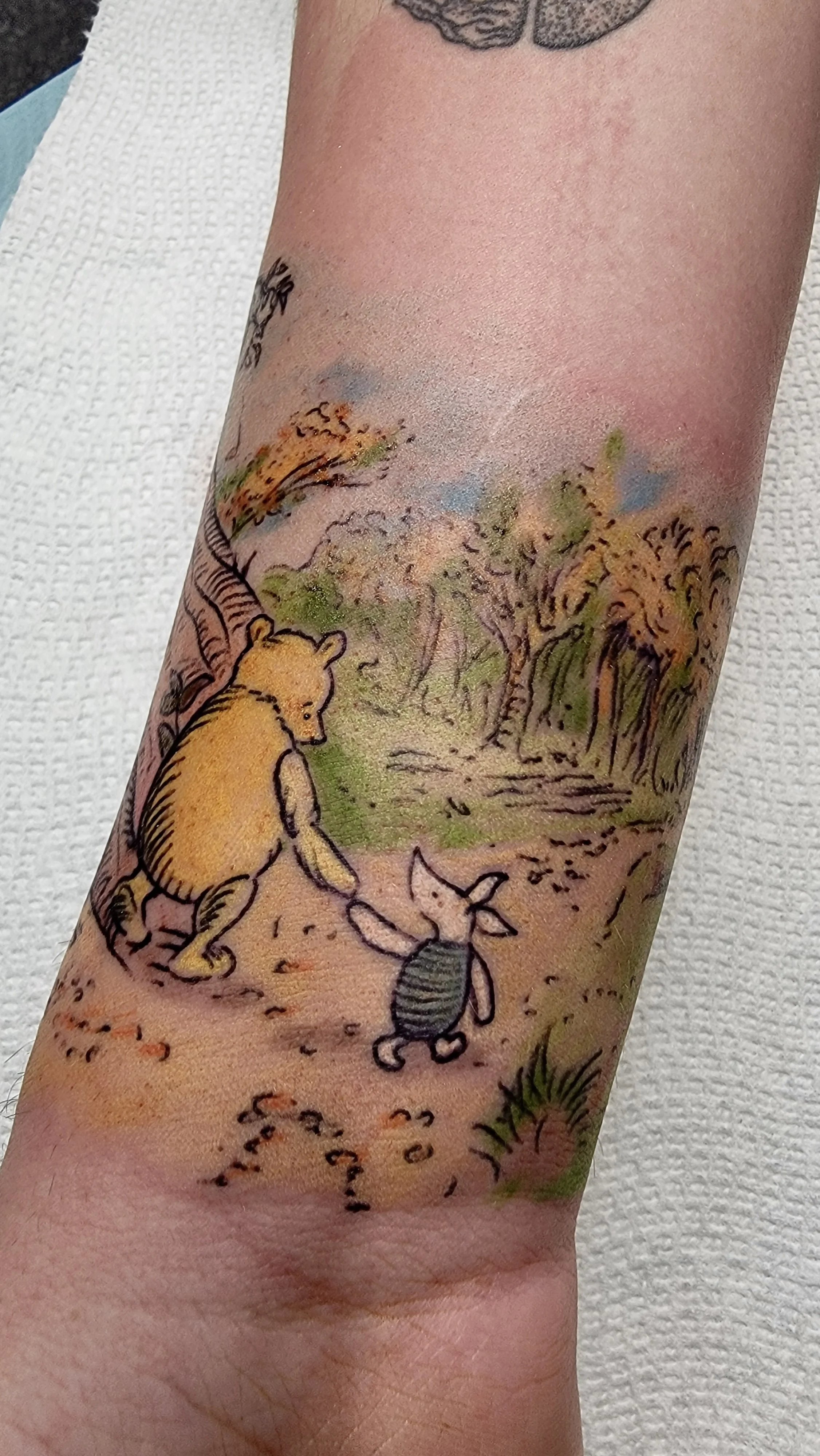 Colorful watercolor style tattoo of woodland scene with a bear, a rabbit, and a bee.