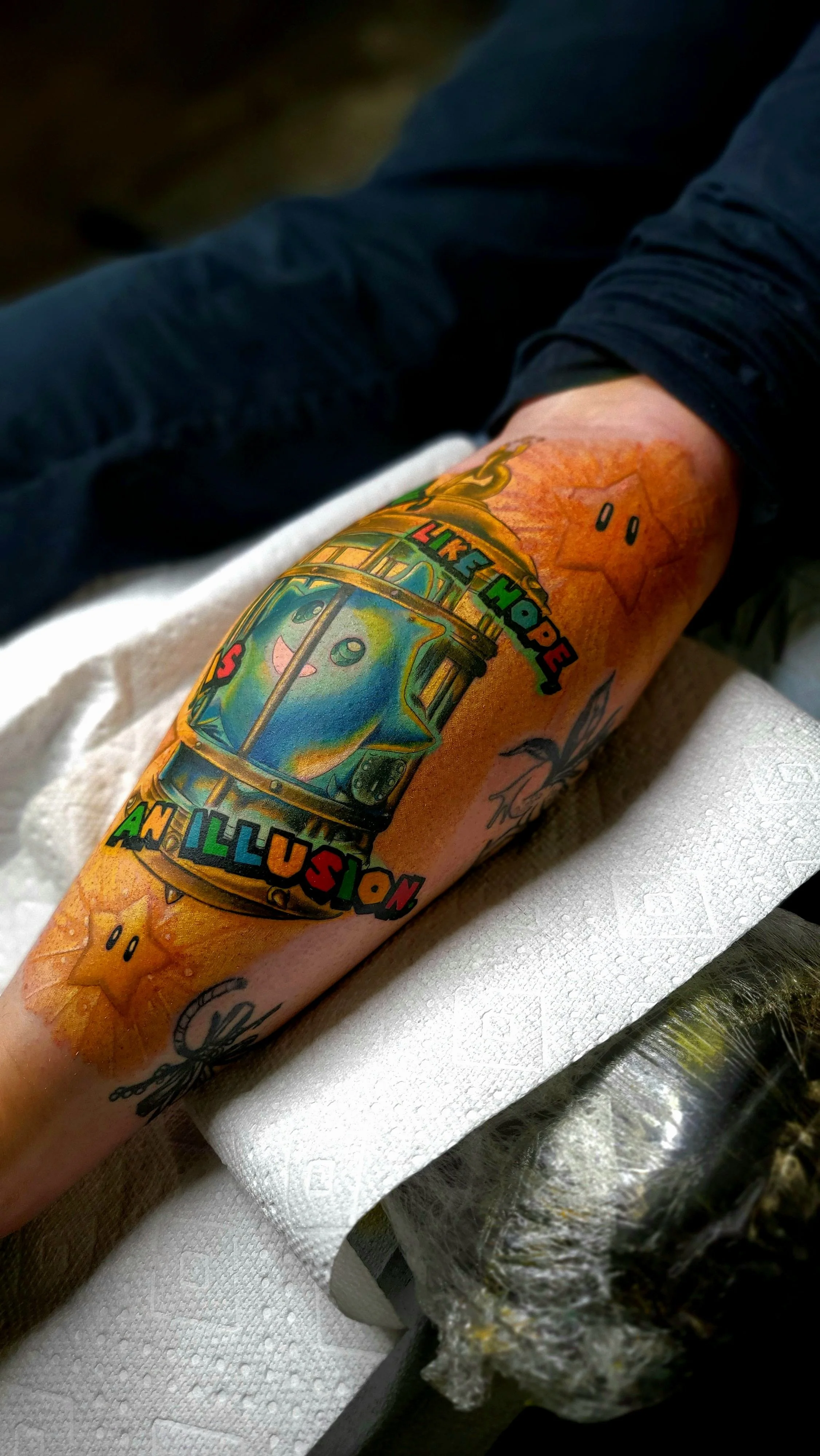 Colorful tattoo of a cheerful cartoonish alien in a spaceship on a person's forearm.