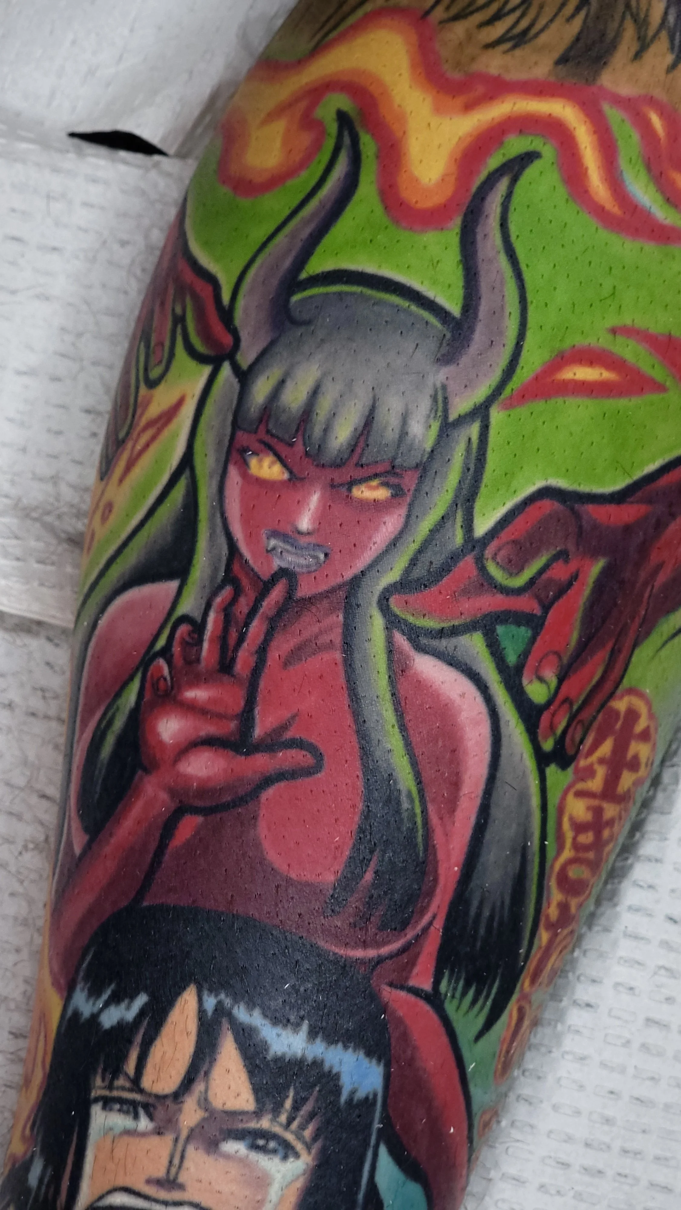 Tattoo artwork of a woman with yellow eyes and gray hair, holding her finger to her lips, with colorful tribal and fire elements around her.
