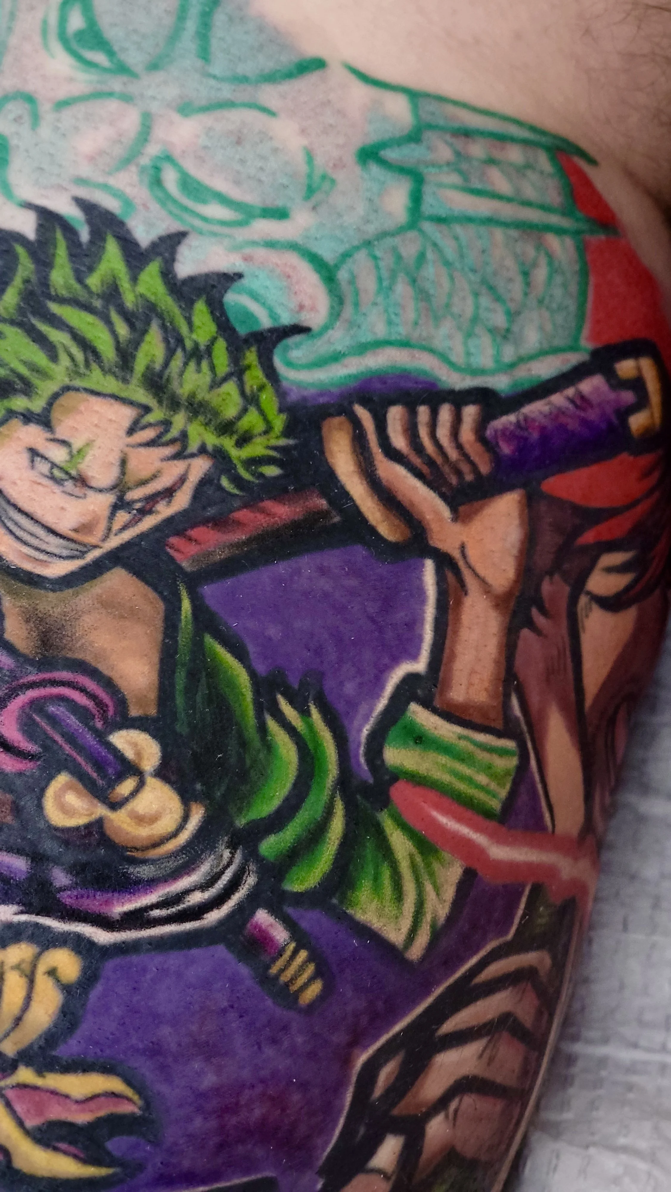 Close-up of a colorful tattoo featuring a cartoon character holding a knife, with green, purple, red, and yellow colors.