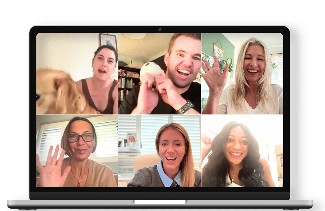 Six people participating in a Zoom video call, smiling and waving, with a dog visible in one participant's frame, and a bookshelf and window in the background.