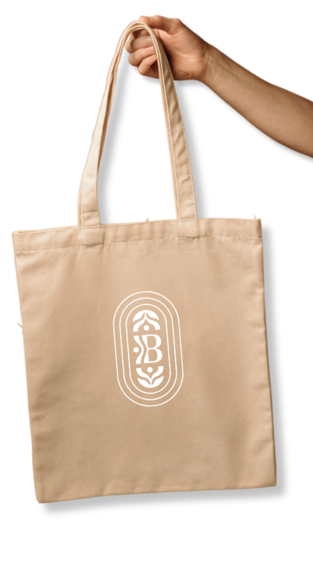 A person holding a beige tote bag with a white logo on the front that features stylized letters 'S', 'B', and 'C' within layered oval shapes.