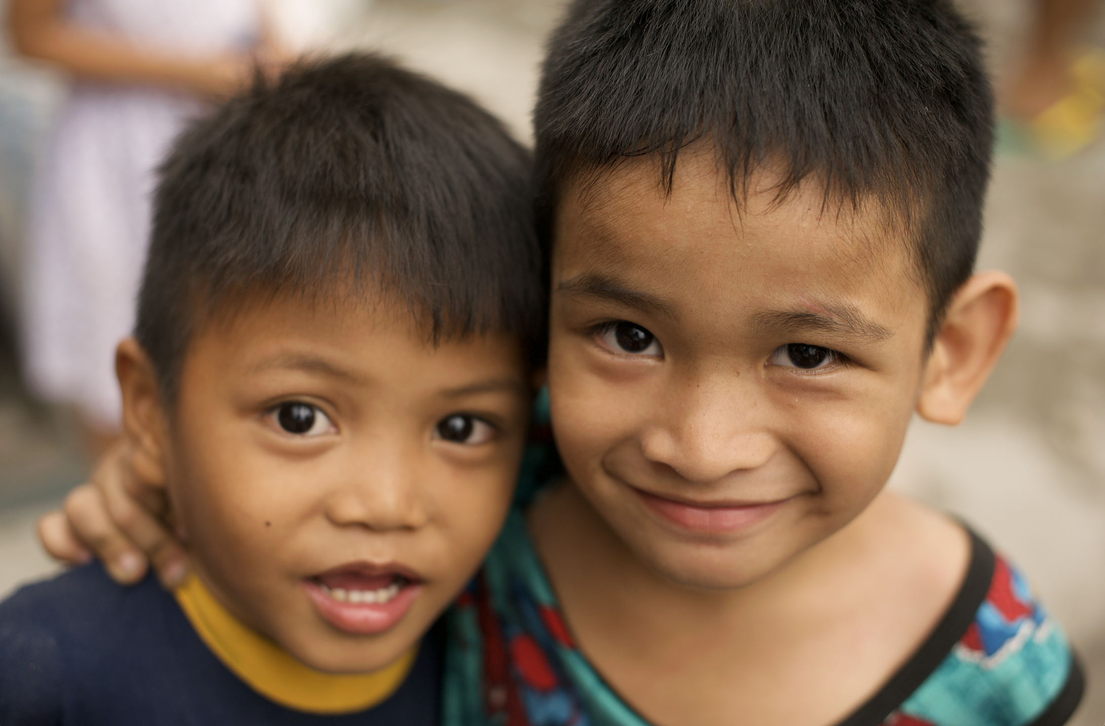 Close-up of two young boys smiling and embracing each other, with blurred background in Tondo, Manila ©R. Hartel for odoVita.