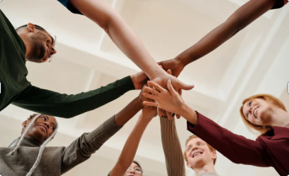 Diverse corporate team joining hands to demonstrate unity, strong company culture, and employee wellness support.