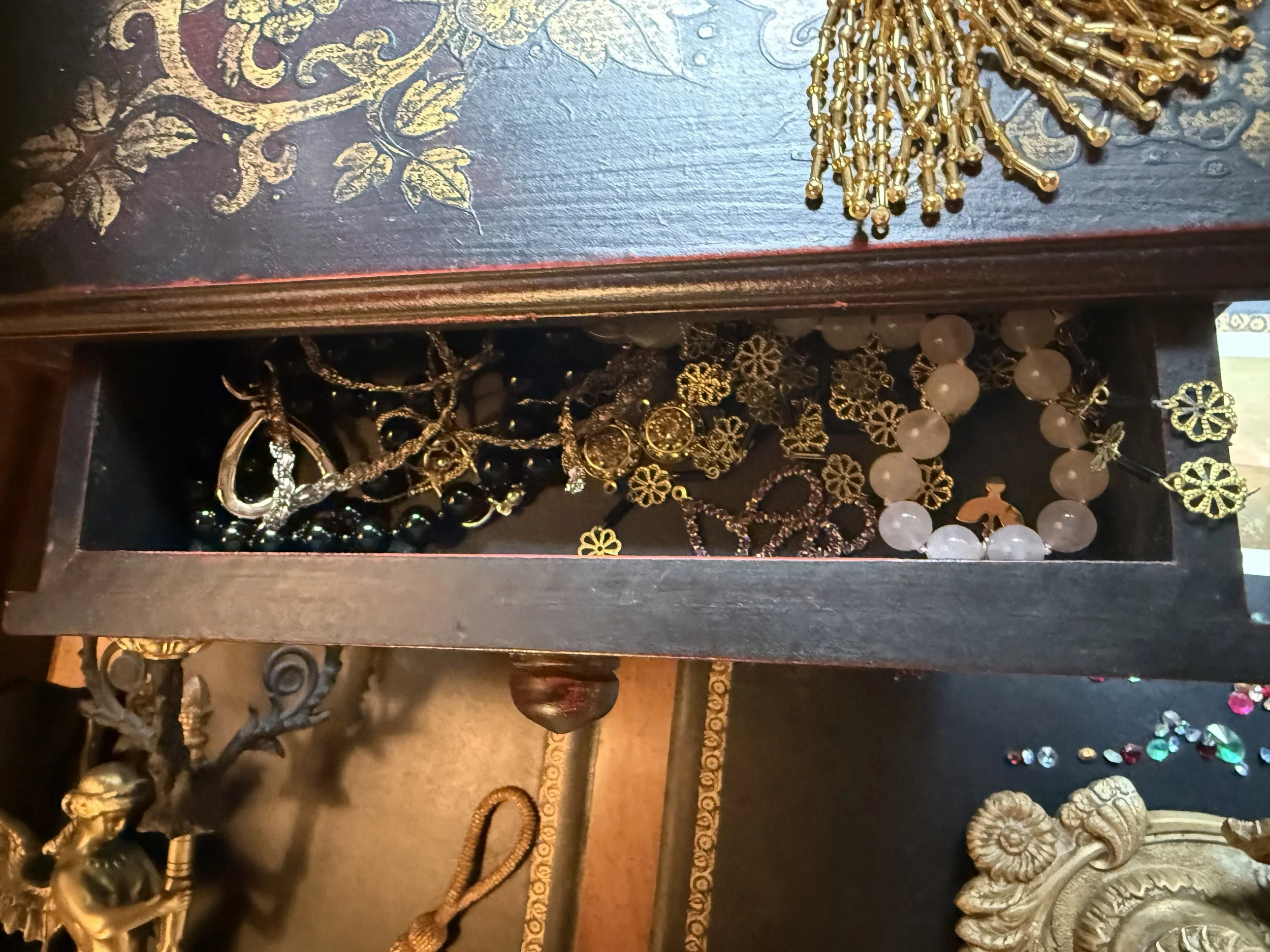 Various jewelry pieces, including gold necklaces, earrings, and bracelets displayed on a dark ornate wooden surface.