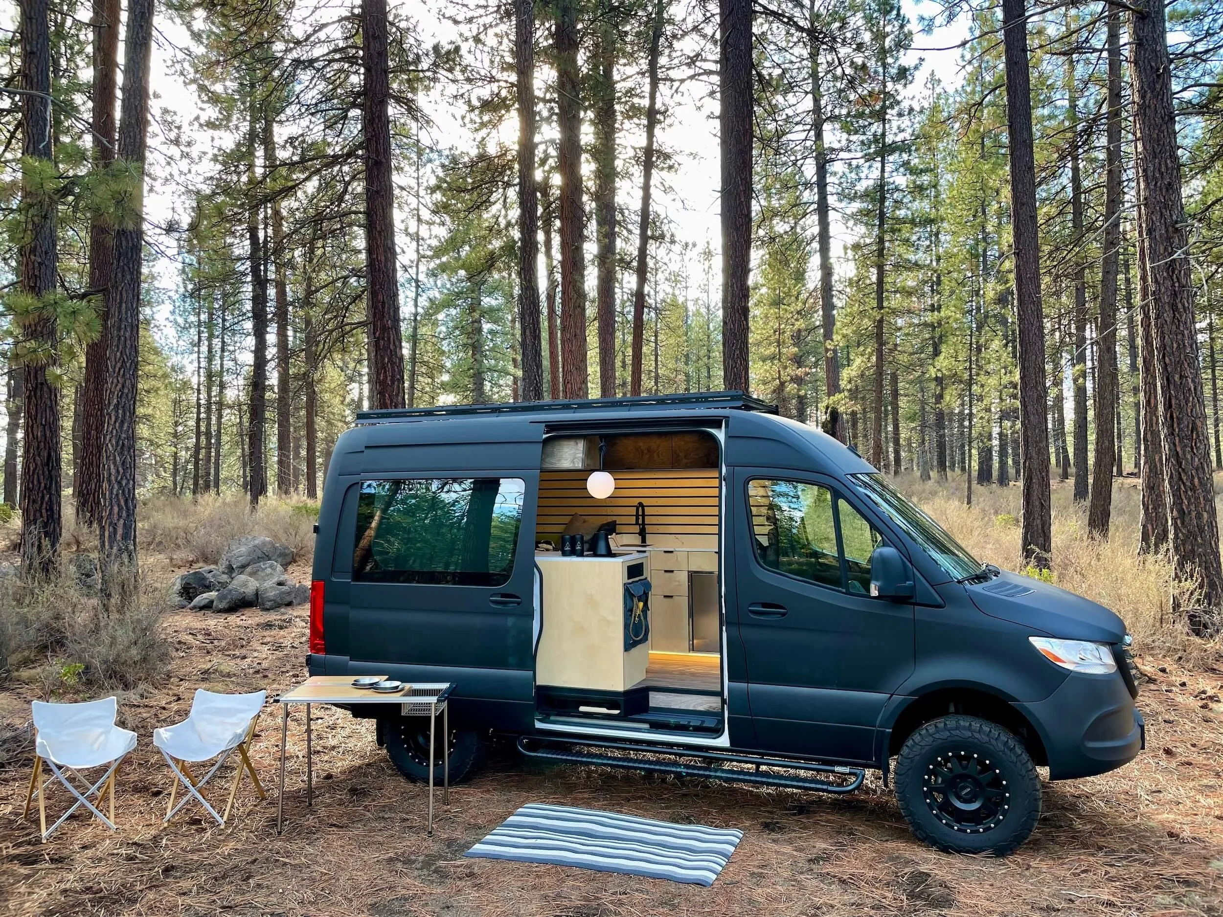 Matte black 'Bellatrix' 144 Sprinter van showcasing custom HWA interior with open slider door