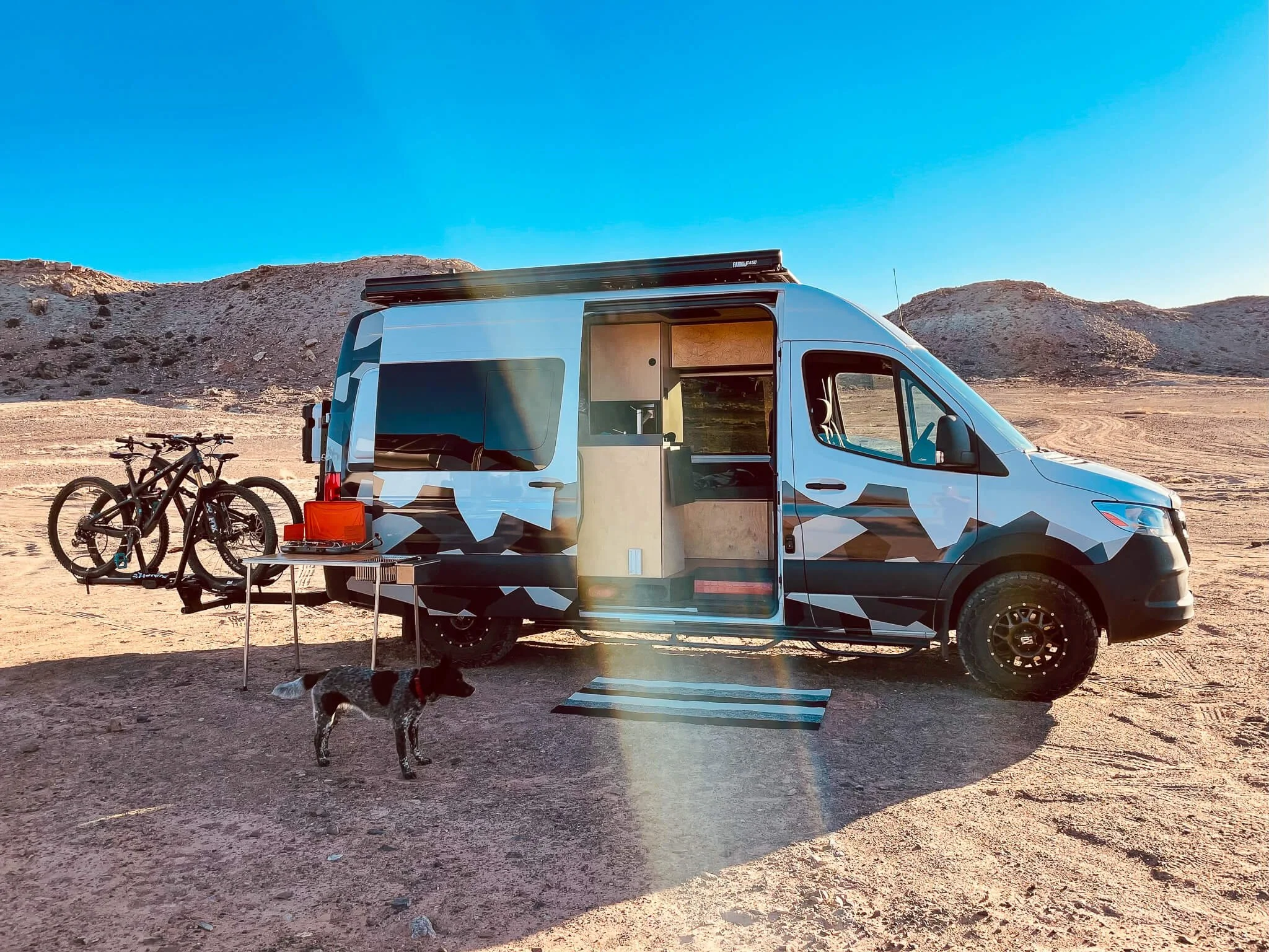 Sprinter 144 with open slider door revealing beautiful interior, accompanied by cattle dog Koda in desert setting
