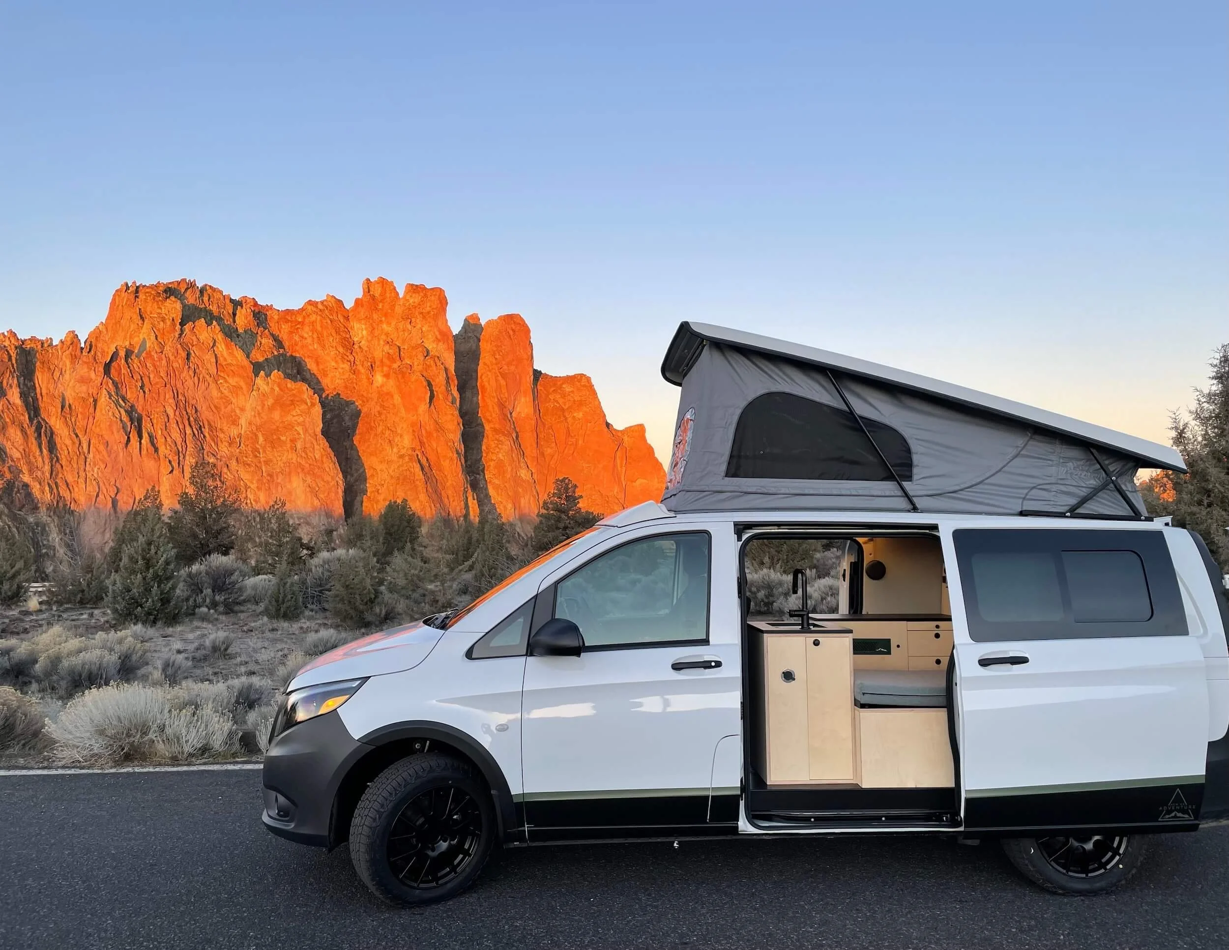 Mercedes Metris van 'Cucumber' displaying custom interior at Smith Rock, Central Oregon, with open doors.