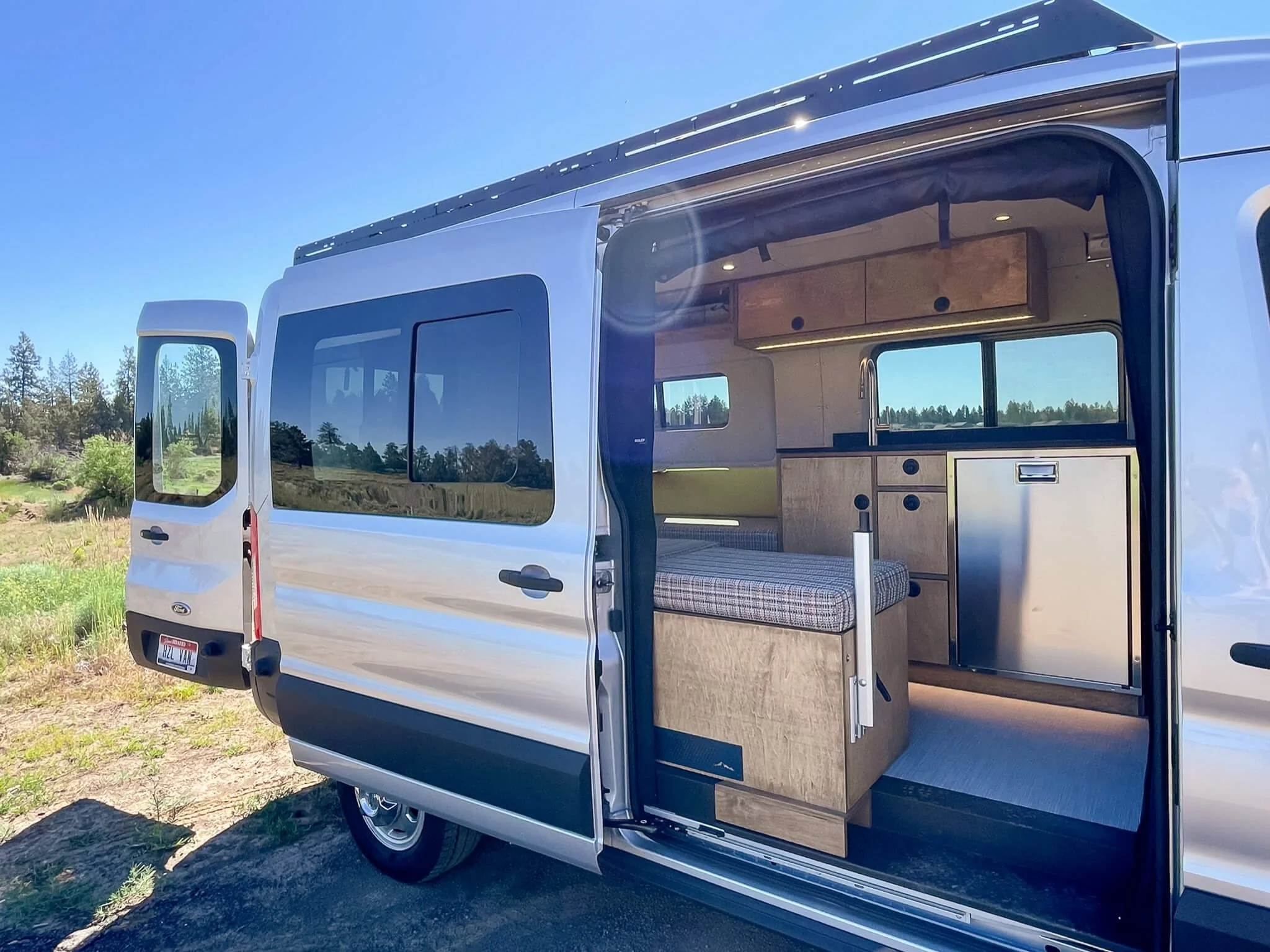 Side angle view of 'HLZVAN' Ford Transit van with open side door, showcasing custom HWA interior.