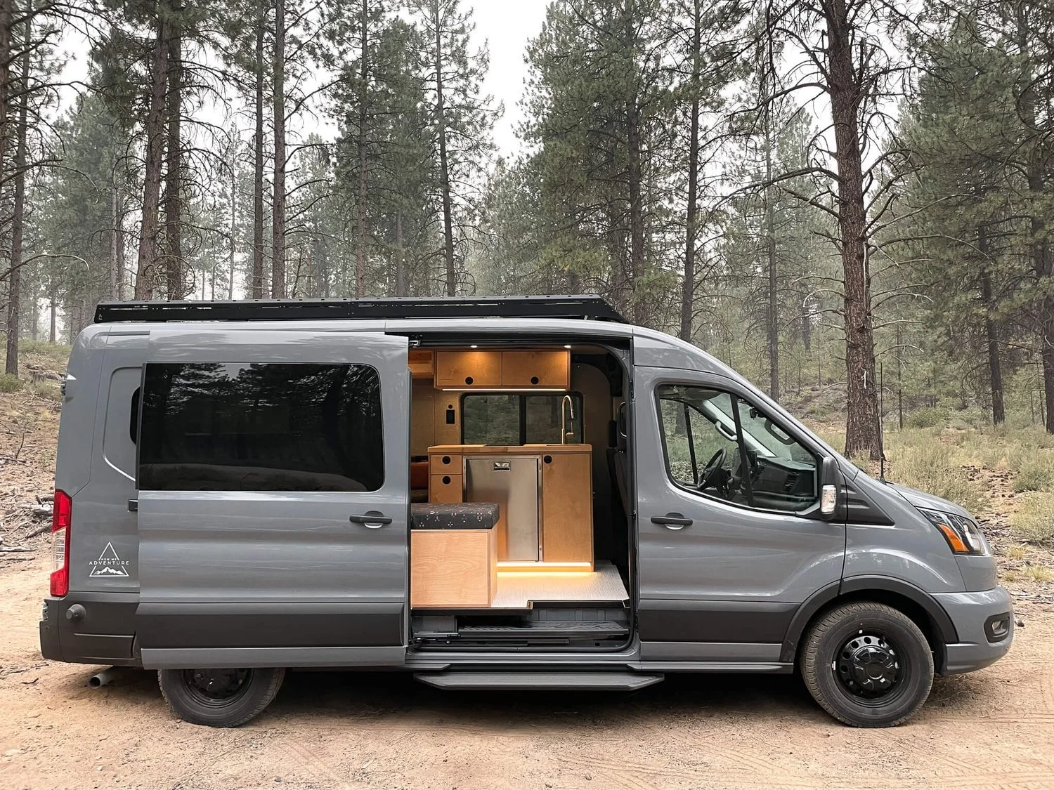 Side view of 'Stanley' Ford Transit van with open side door, showcasing custom How We Adventure interior.