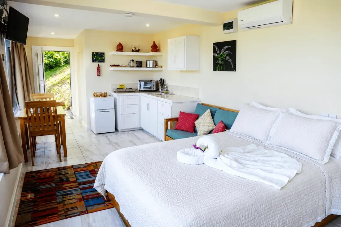 Open-plan studio villa in Coubaril, Saint Lucia, with a bed, kitchenette and large windows