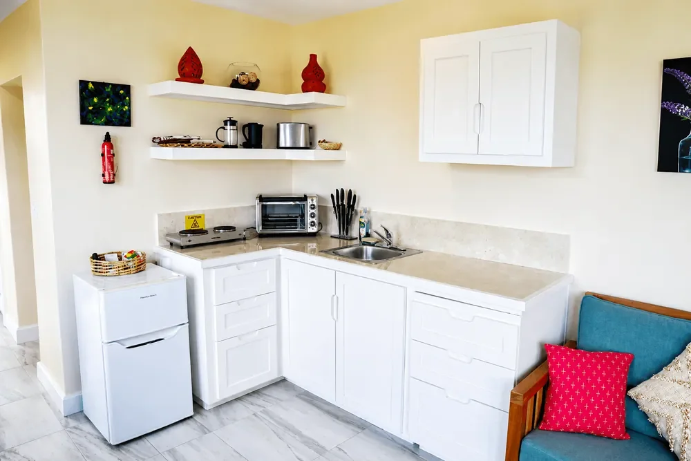 Kitchenette in the Memwa studio villa, with white cabinets and a mini fridge