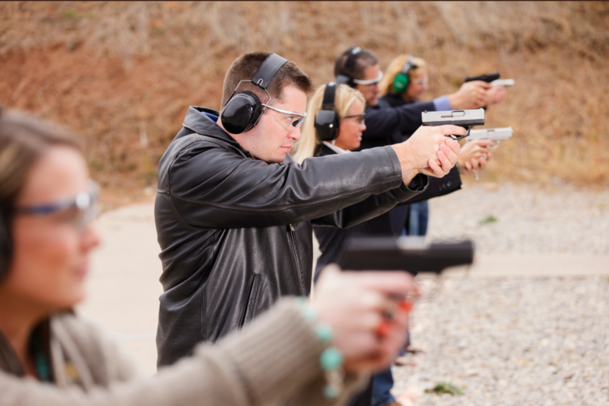 Team Training: A group of adults practicing pistol shooting side by side at an outdoor range