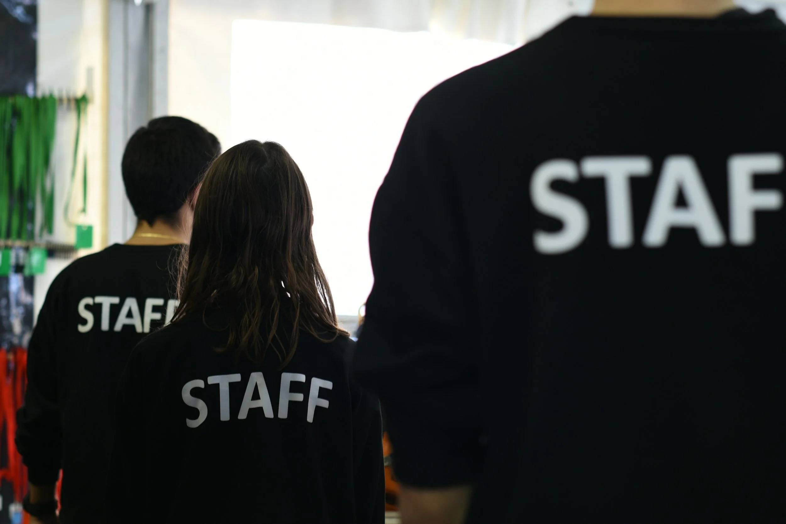 Group of people wearing black staff shirts, standing in line indoors.