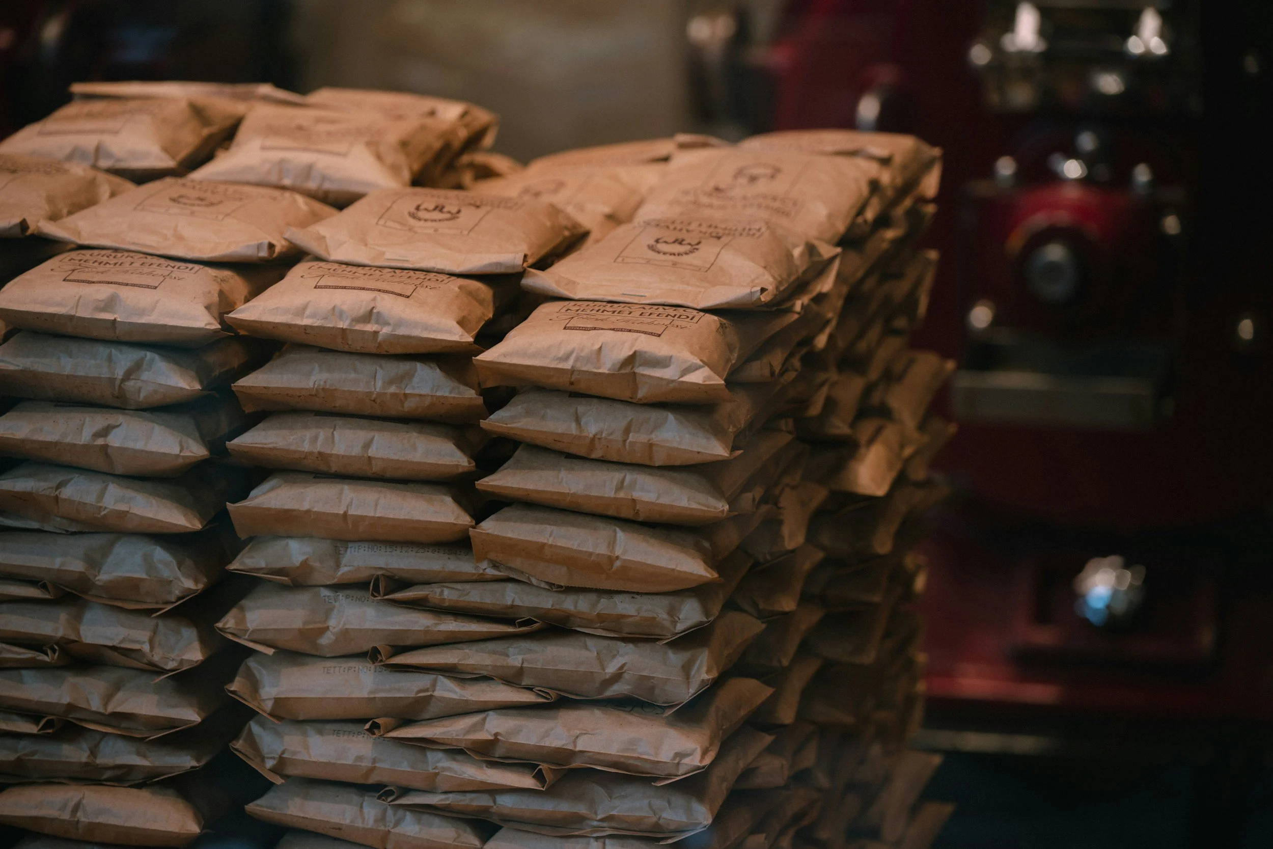 Stack of brown paper bags labeled with a coffee logo, arranged on a shelf or counter.