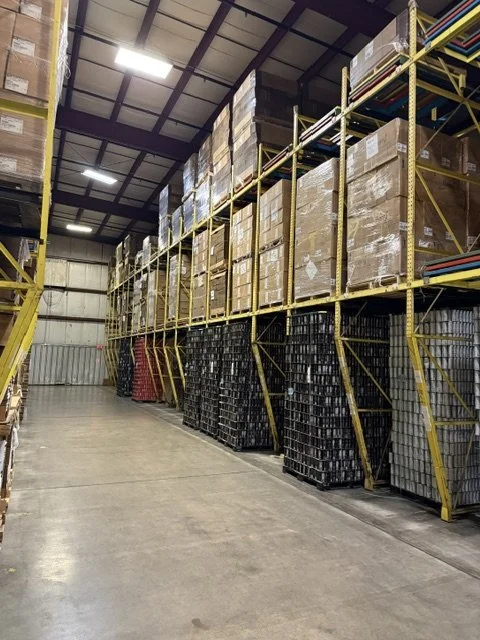 Warehouse aisle with tall shelves stacked with boxes and black plastic containers