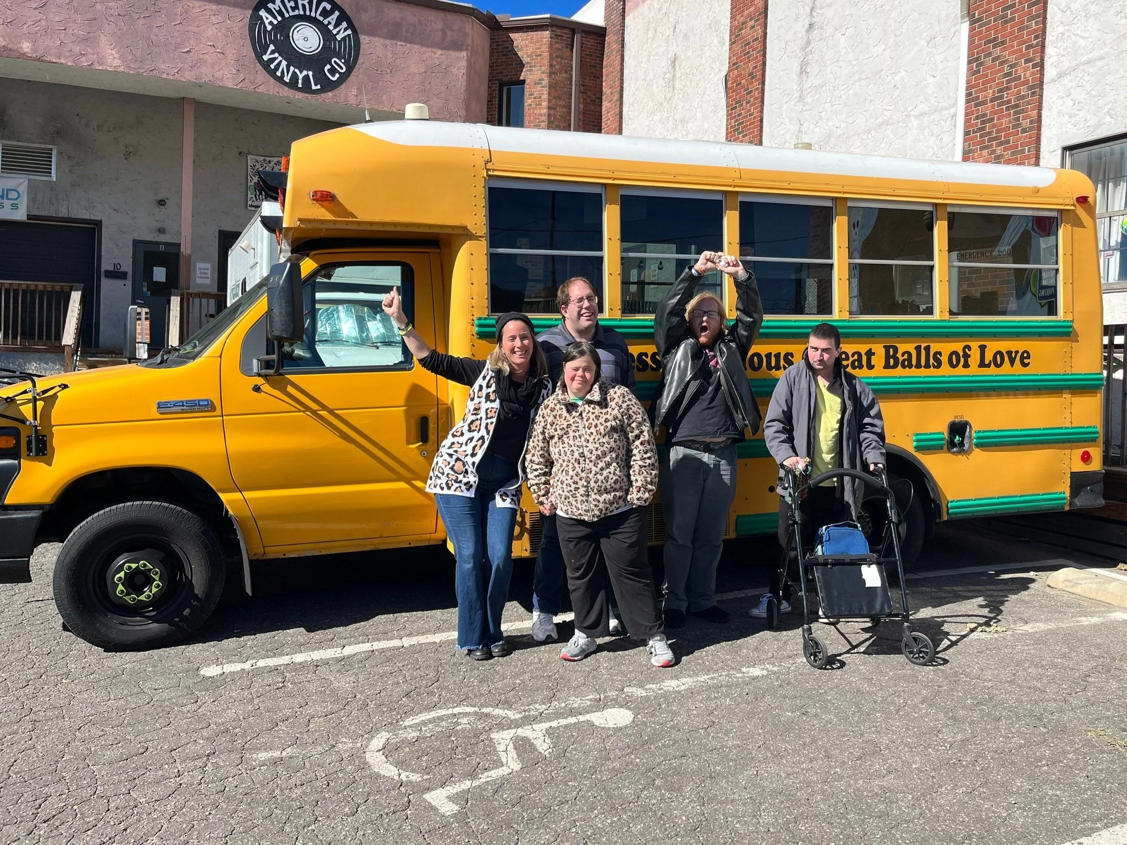 People with disabilities and their coach celebrating workplace success in front of a bus