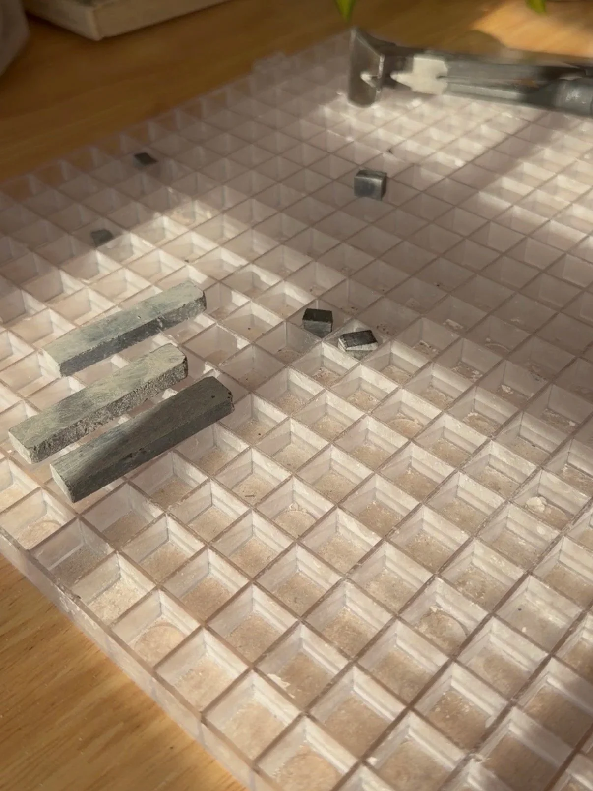 Close-up of a mosaic tile grid with some marble stone tiles on top.