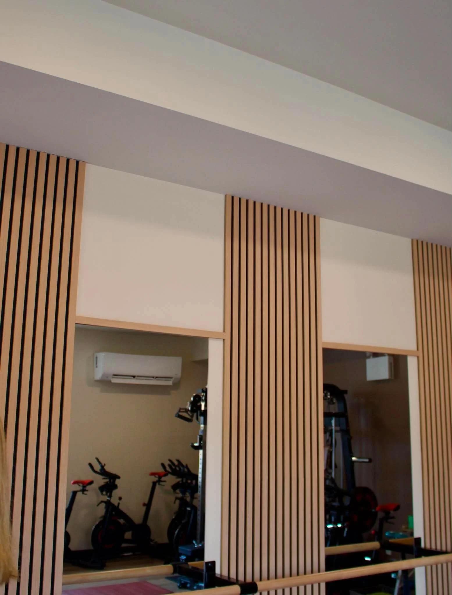Indoor gym with bicycles, exercise equipment, and wooden wall panels.
