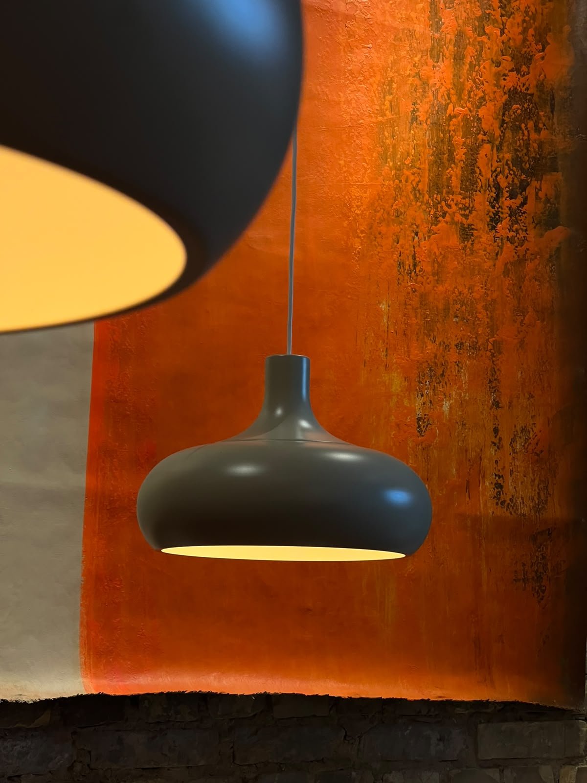 Hängende schwarze Deckenlampe vor einer orangefarbenen Wand