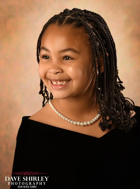 Smiling kindergarten student wearing a black velvet graduation portrait drape