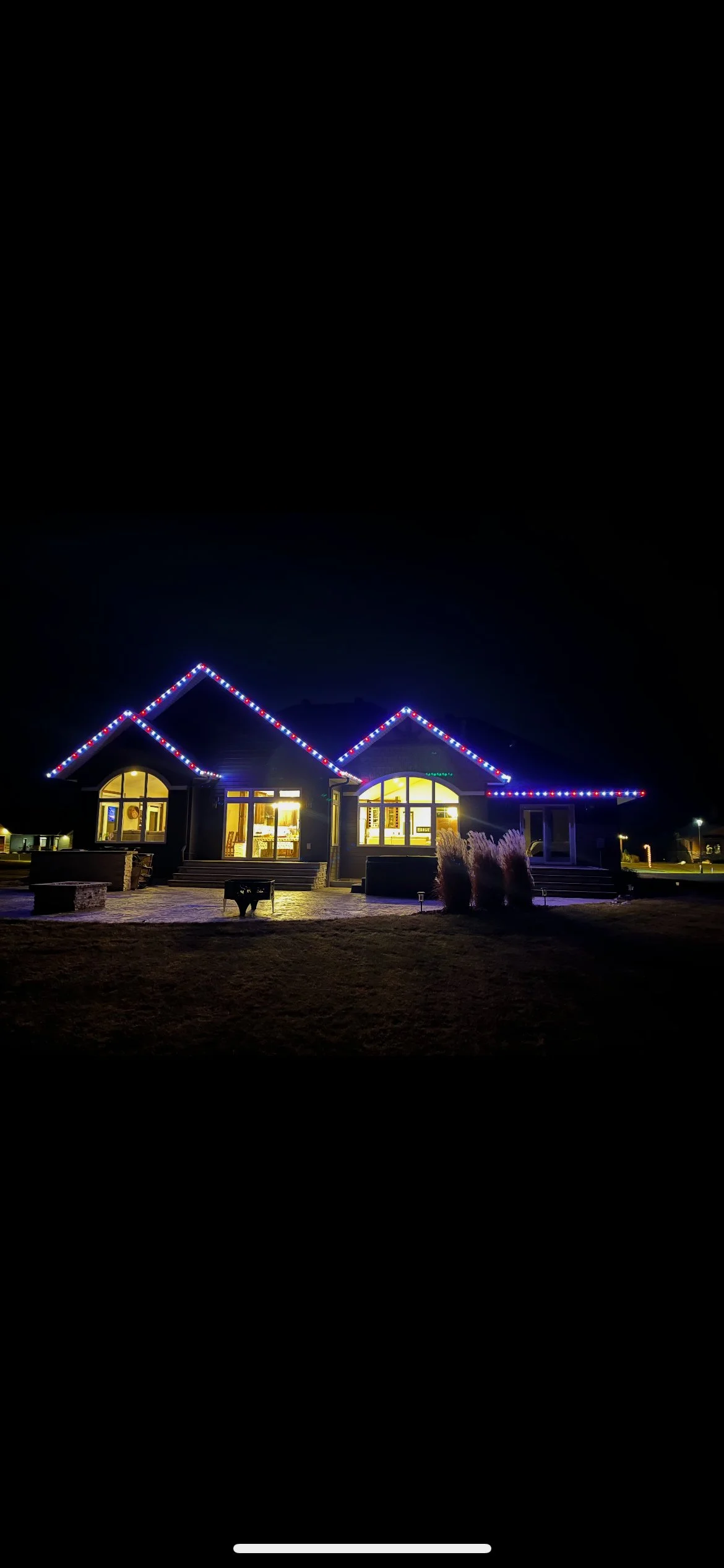 Home at night with two lit gables and permanent roofline lighting in red, white, and blue