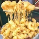 Close-up of cheesy macaroni and cheese being lifted with a fork