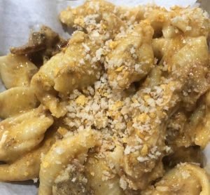 Close-up of a serving of banana fritters topped with crumbled cheese or powdered sugar.