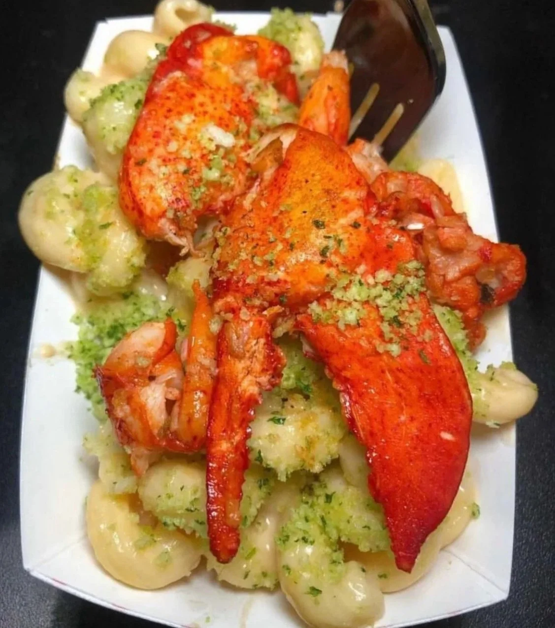 Lobster tail served with broccoli and potatoes, garnished with herbs.