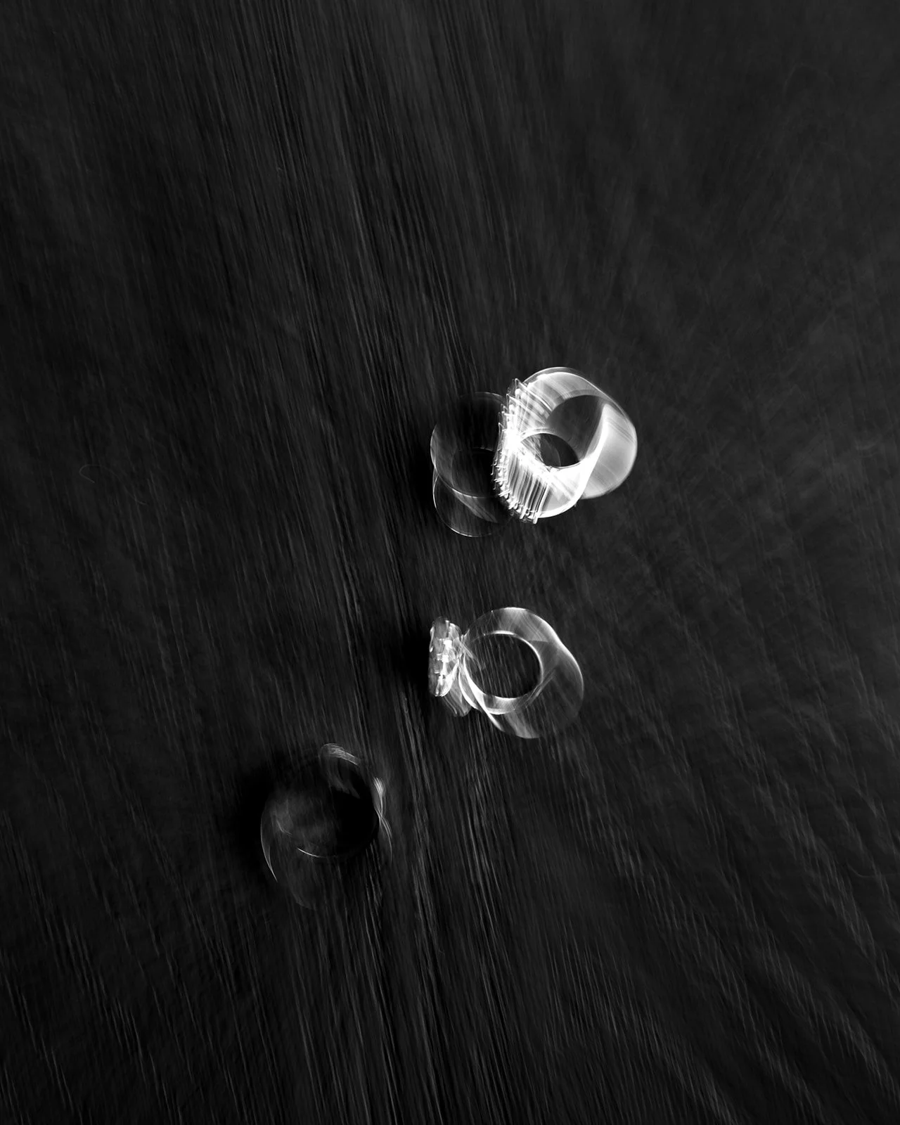 Scattered clear glass rings on a dark wooden surface.