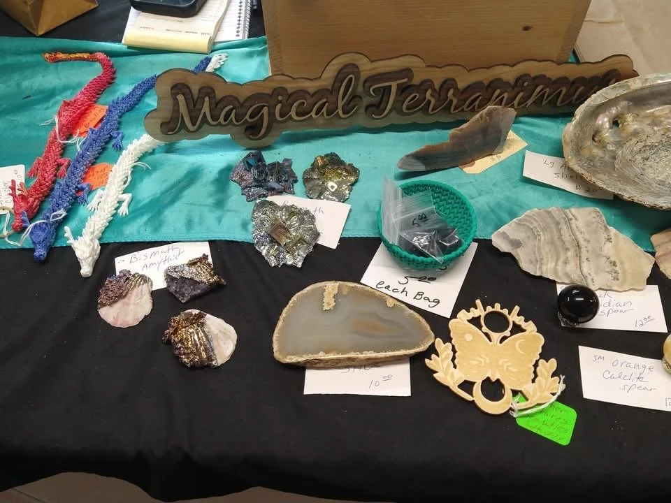 A display table with various minerals, rocks, and shells, along with a wooden sign reading 'Magical Terrarium.'
