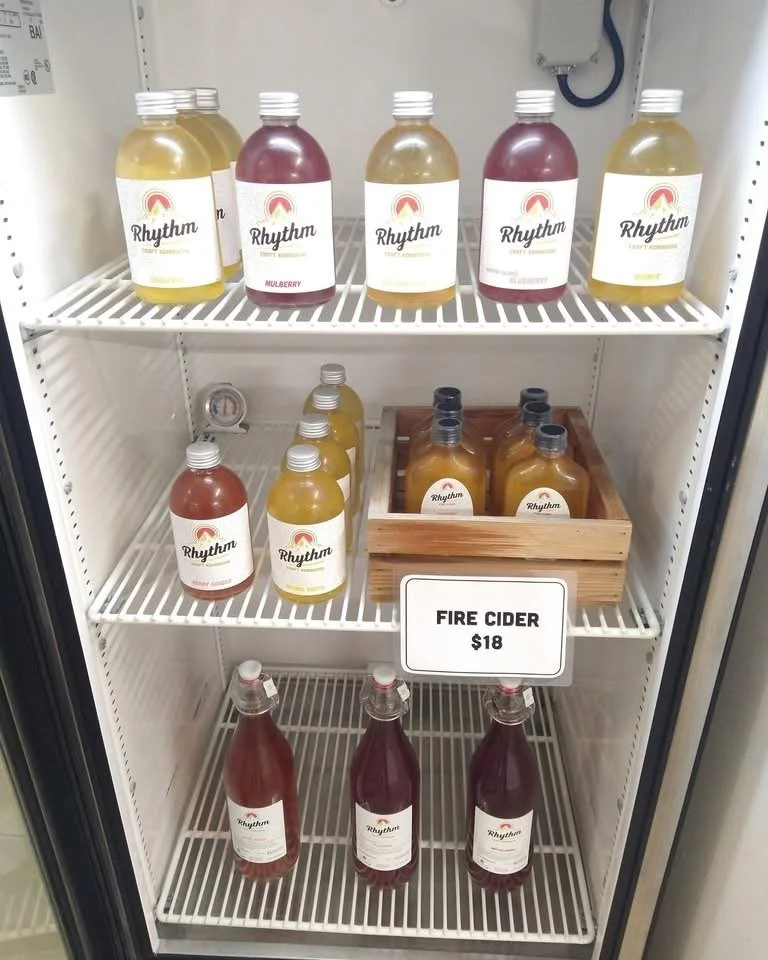 A refrigerator with bottles of different flavored cider, including fire cider priced at $18.