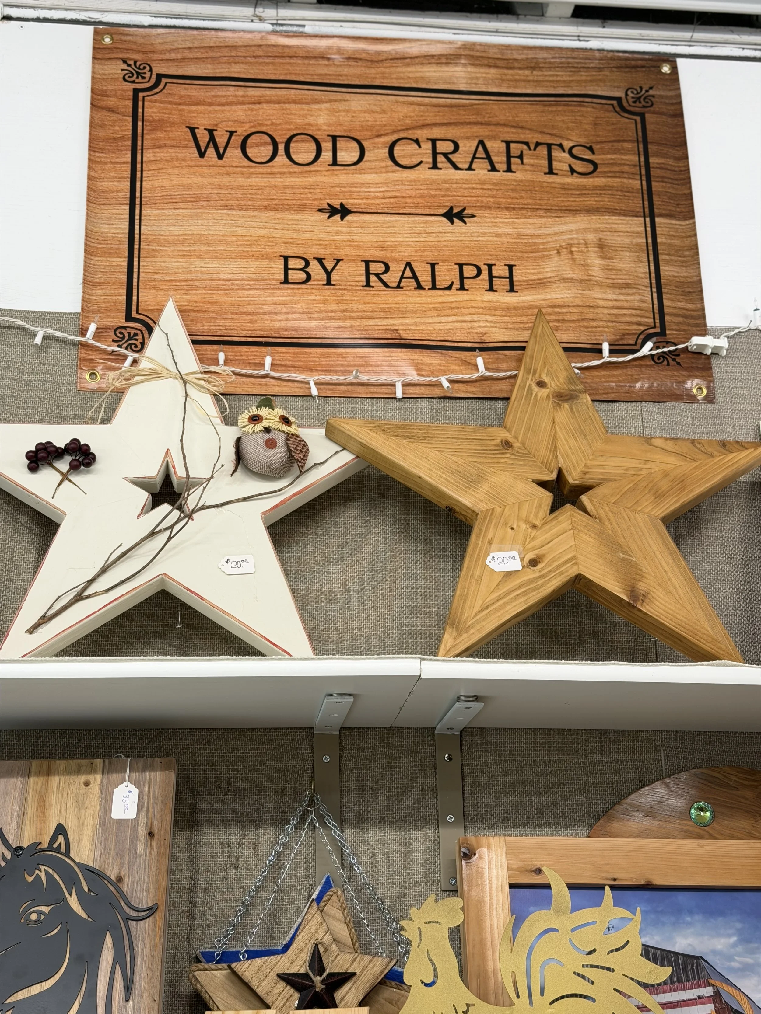 Wood crafts sign by Ralph surrounded by various decorative wooden items including stars, a unicorn, and pumpkins.