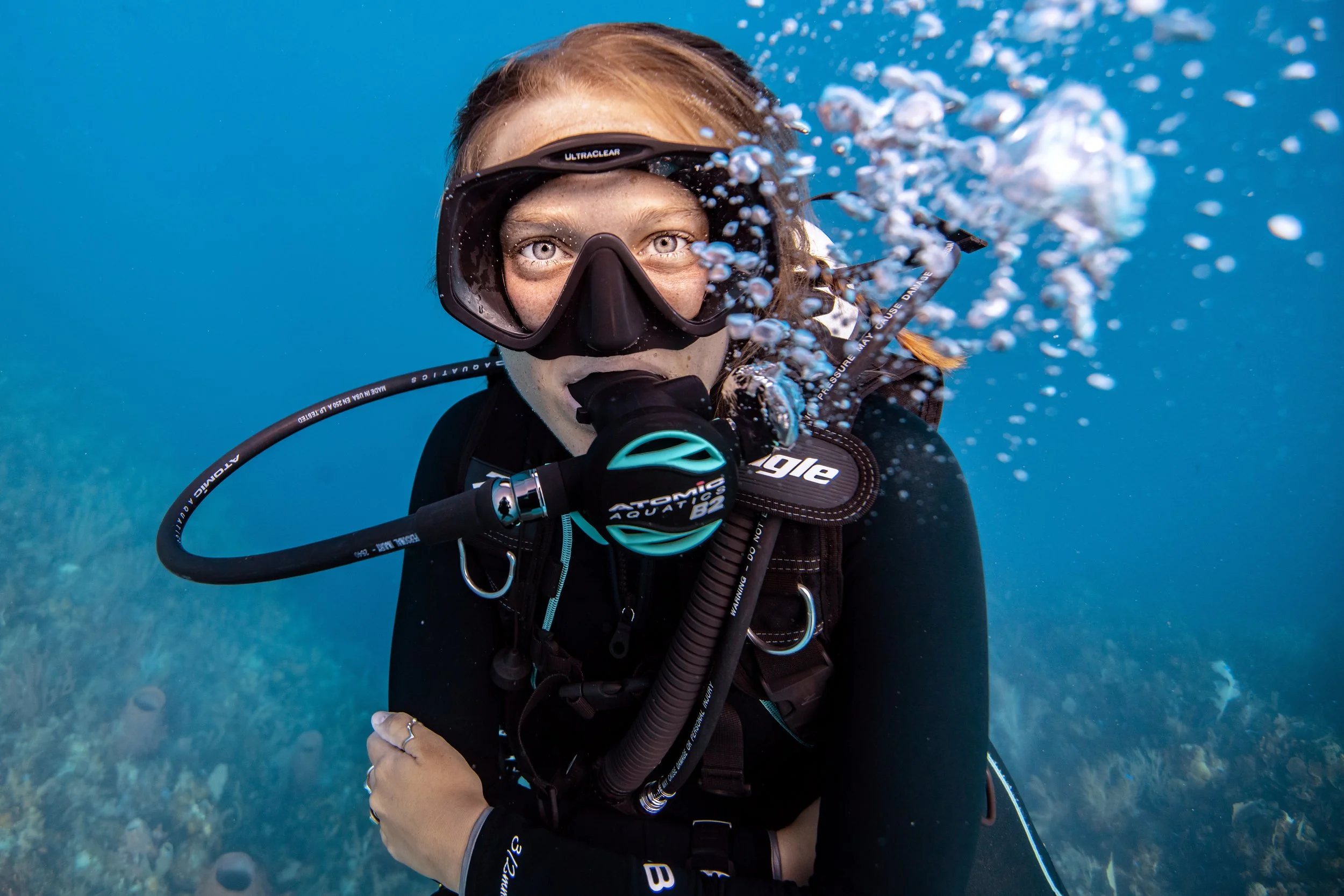 female scuba diver smiling at the camera under water