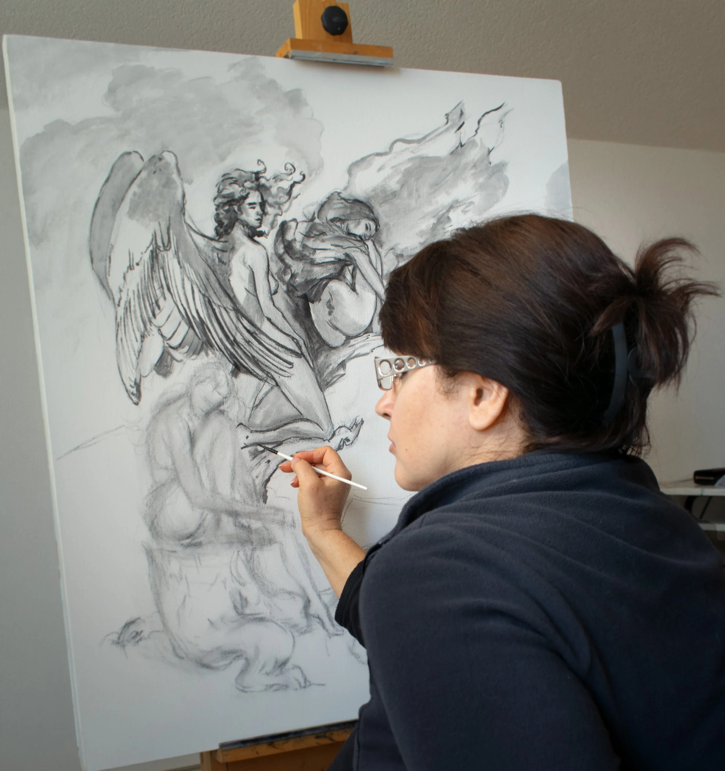 Nika Nyoko working on an angel, on a large canvas. The artist is deeply focused on their work, paintbrush in hand, as they meticulously bring their vision to life within the studio.