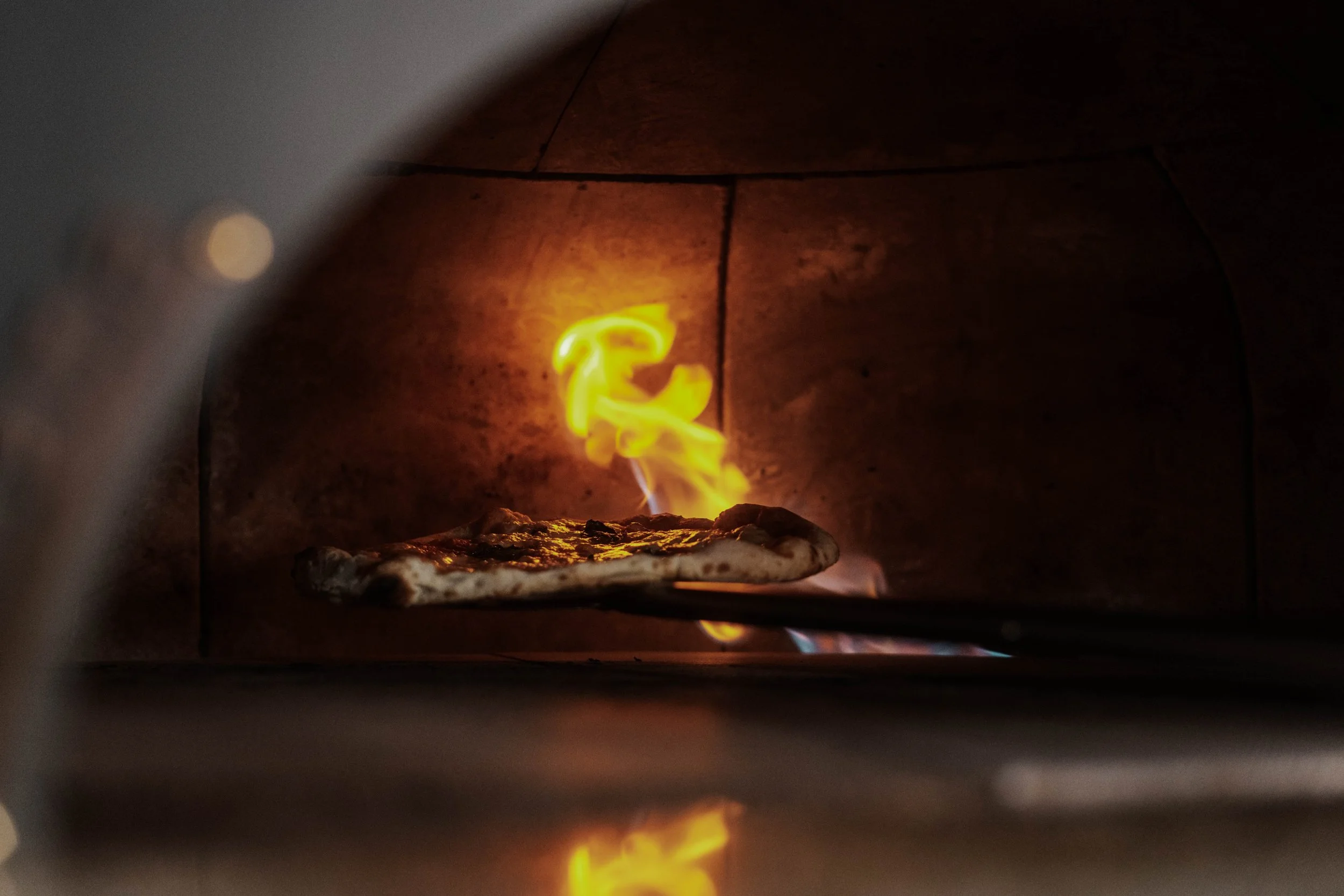 Neapolitan Pizza cooking inside a traditional dome shaped Neapolitan pizza oven