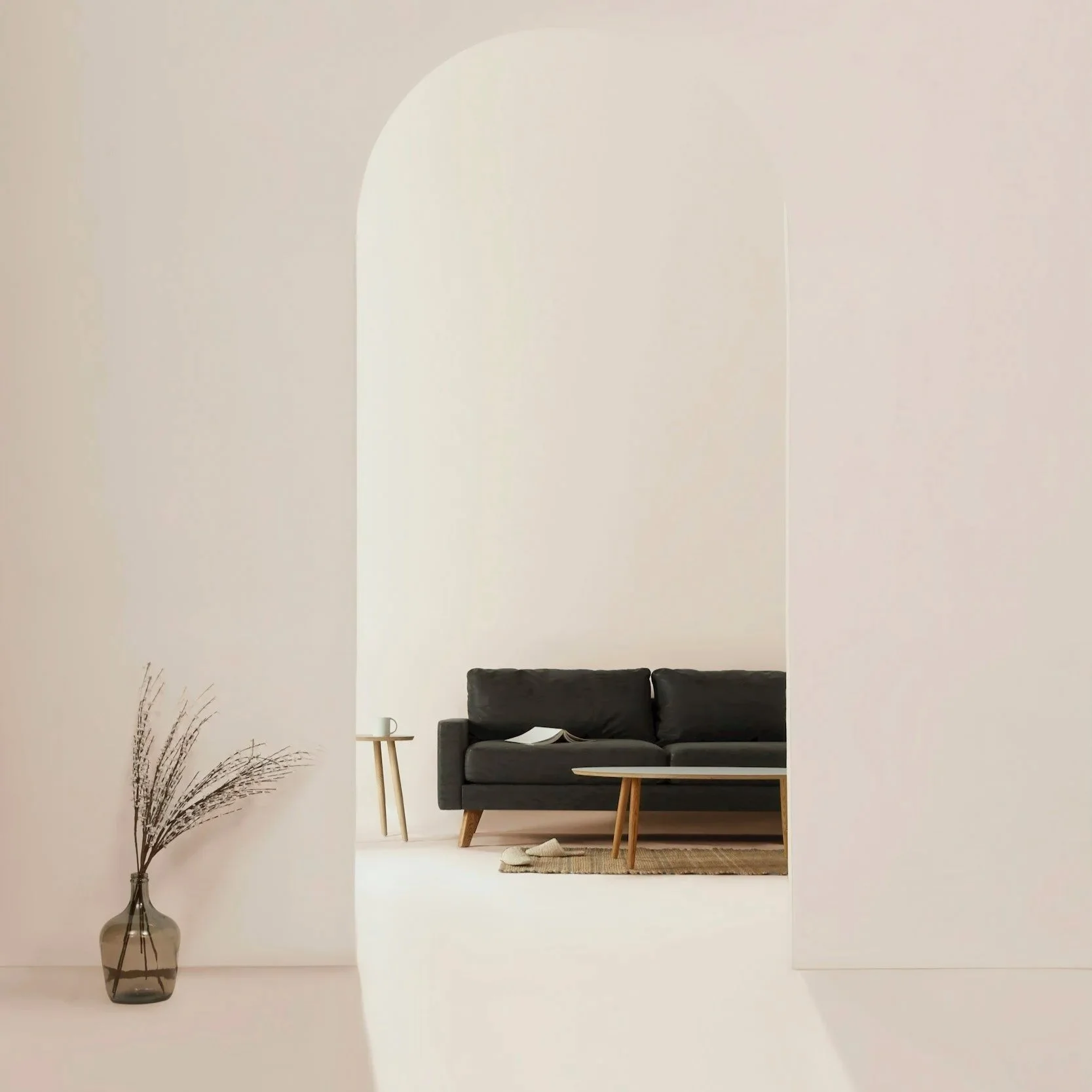 Modern living room with a black sofa, wooden coffee table, side table, books, and a decorative vase with dried plants, viewed through an open doorway.
