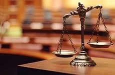 Bronze scales of justice on a desk in a courtroom setting