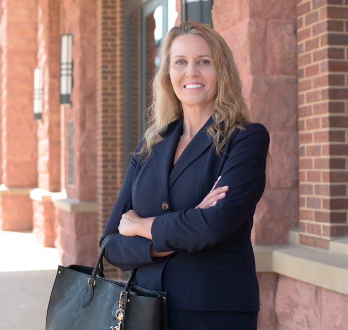 Lisa Martin standing outside in a navy blazer, arms crossed