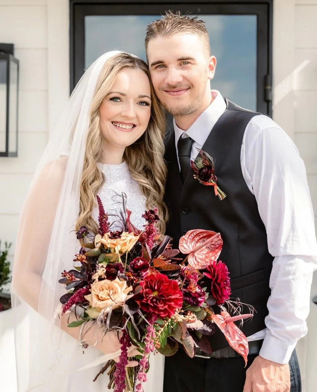 bride with soft glam makeup smiling happy with husband on wedding day with fall color bouquet